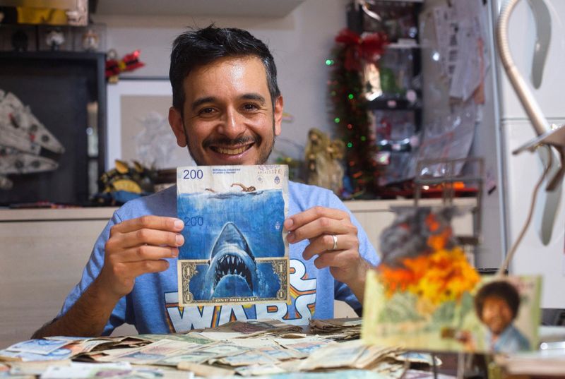 El artista Sergio Díaz sostiene billetes de pesos argentinos intervenidos y un dólar estadounidense que representan la película "Tiburón" de Steven Spielberg como una parodia de la inflación cada vez mayor de Argentina, en Salta, Argentina. Dic 30, 2022. REUTERS/Javier Corbalan