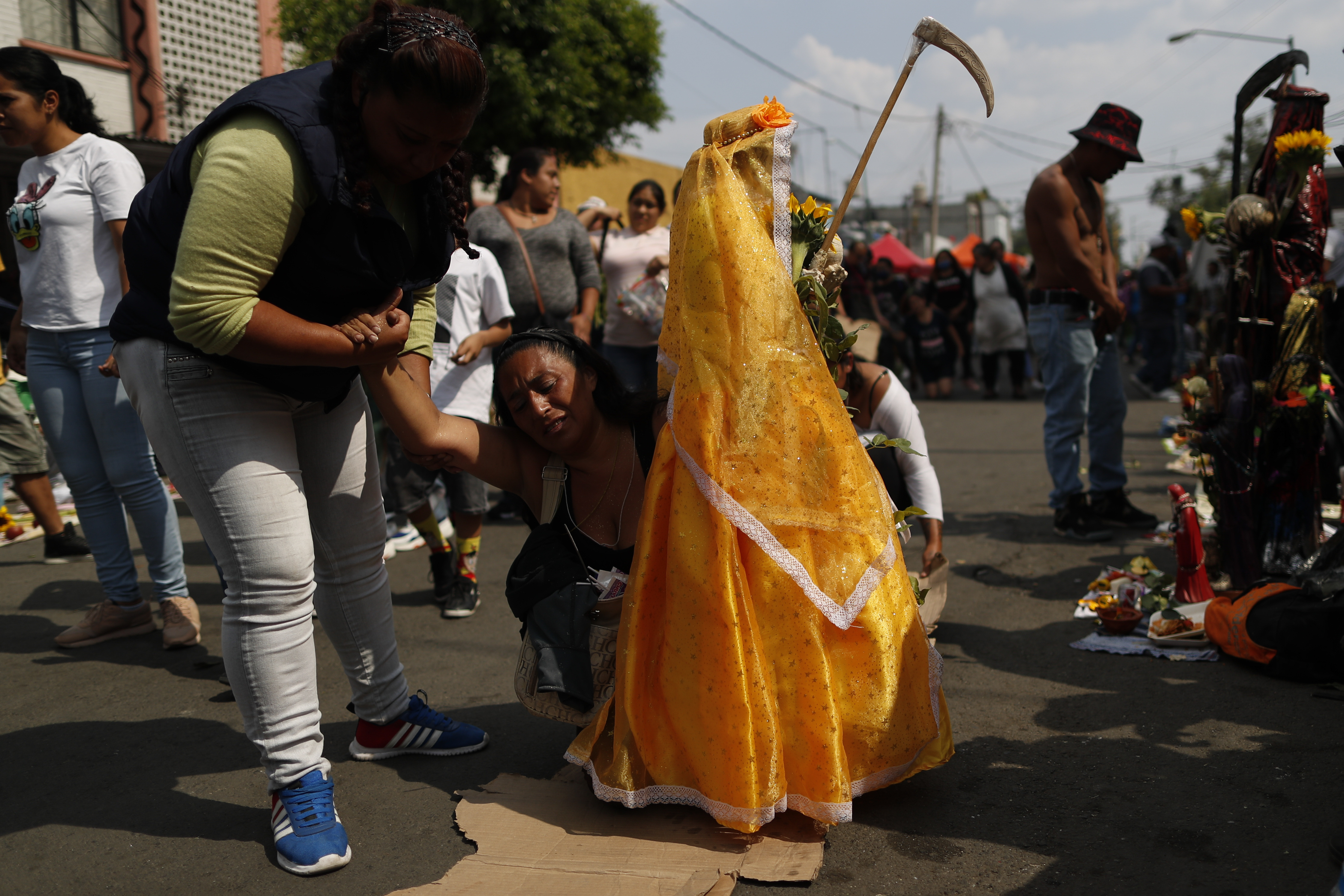 Una amiga ayuda a Victoria Moreno, de 43 años, quien lucha por llegar de rodillas al altar de la Santa Muerte, una promesa que Moreno había hecho al pedirle a la santa que ayudara a salvar a su hija que sufría de apendicitis. (Foto: AP / Rebecca Blackwell)