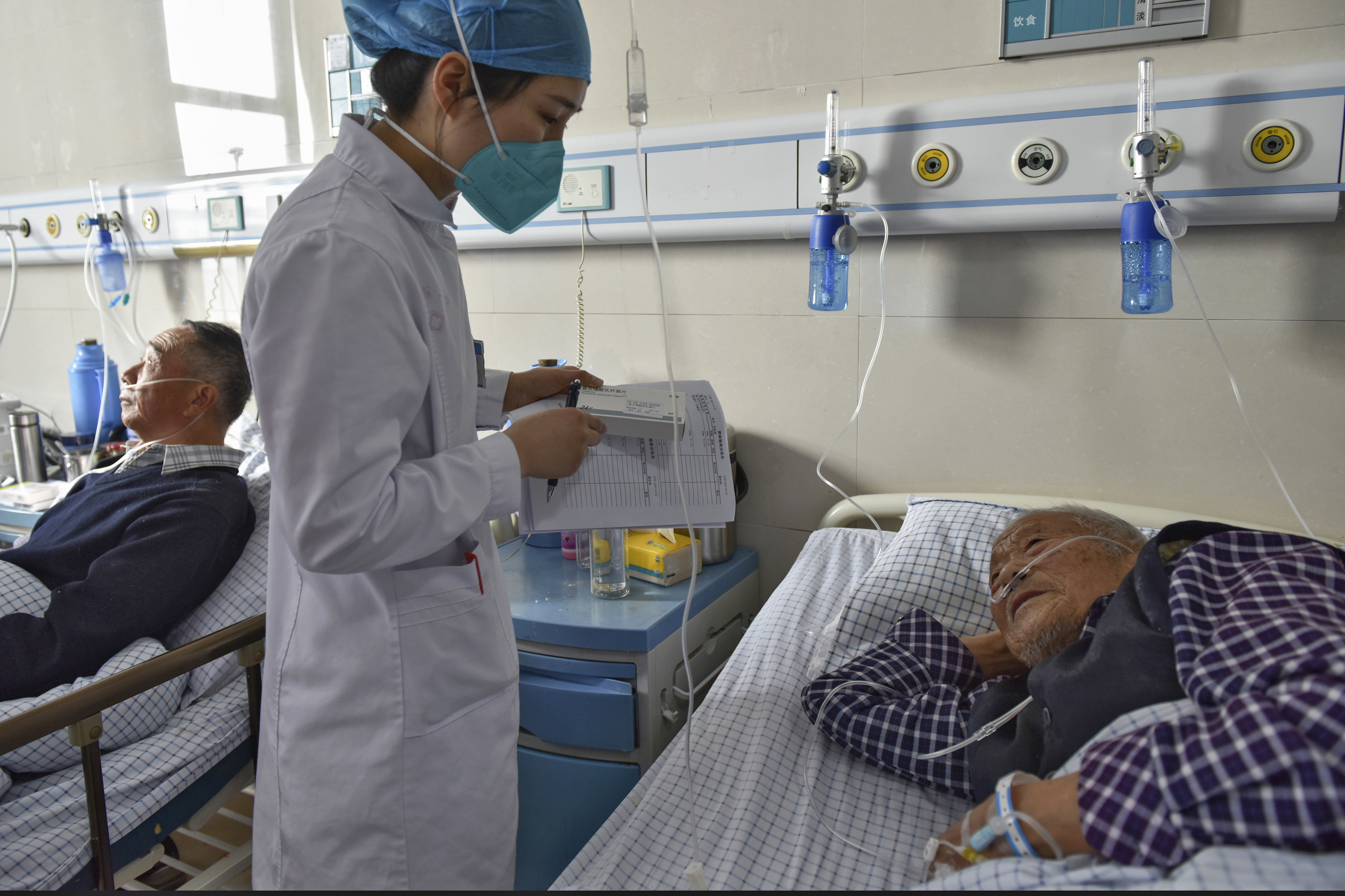 A nurse gives a medication talk to an elderly patient while he is receiving an IV (Chinatopix Via AP)