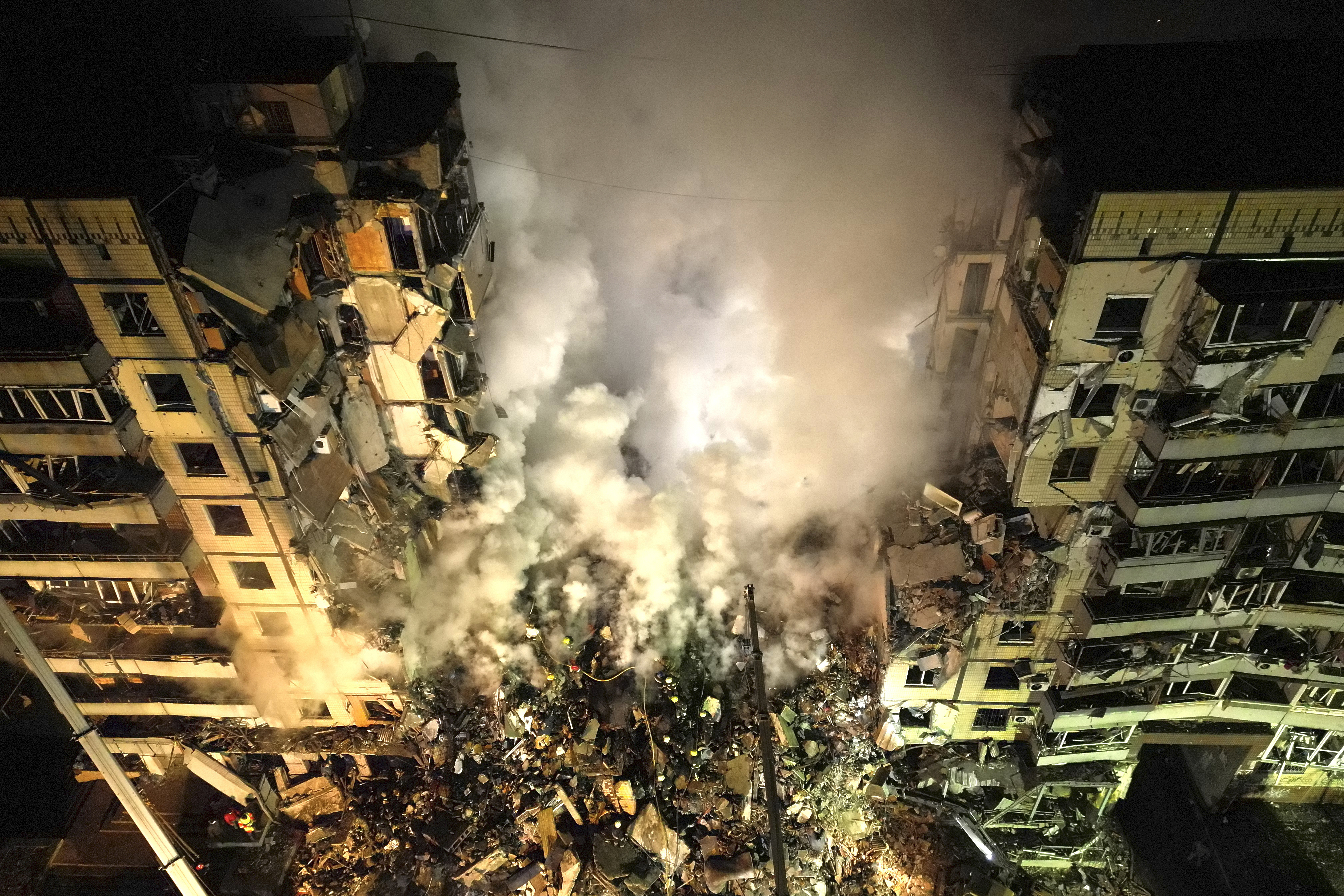 Trabajadores de emergencias retiran escombros después de un ataque ruso contra un edificio de apartamentos que atrapó a mucha gente bajo los escombros en la ciudad suroriental de Dnipro, Ucrania, el sábado 14 de enero de 2023. (AP Foto/Evgeniy Maloletka)