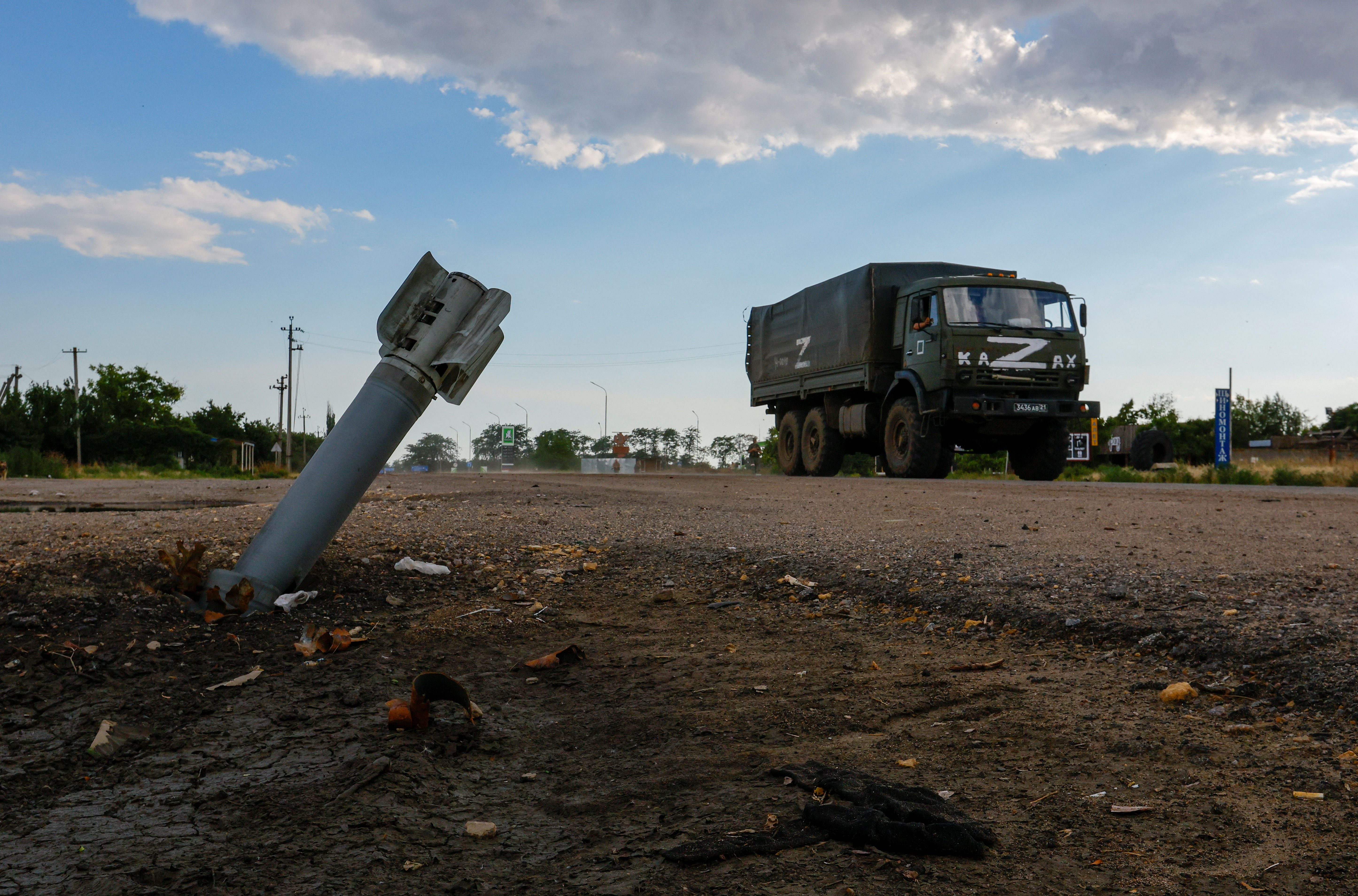 Un camión militar ruso pasa junto a una munición sin explotar durante el conflicto Ucrania-Rusia en la aldea de Chornobaivka, Ucrania, controlada por Rusia, el 26 de julio de 2022 (Foto: REUTERS/Alexander Ermochenko)