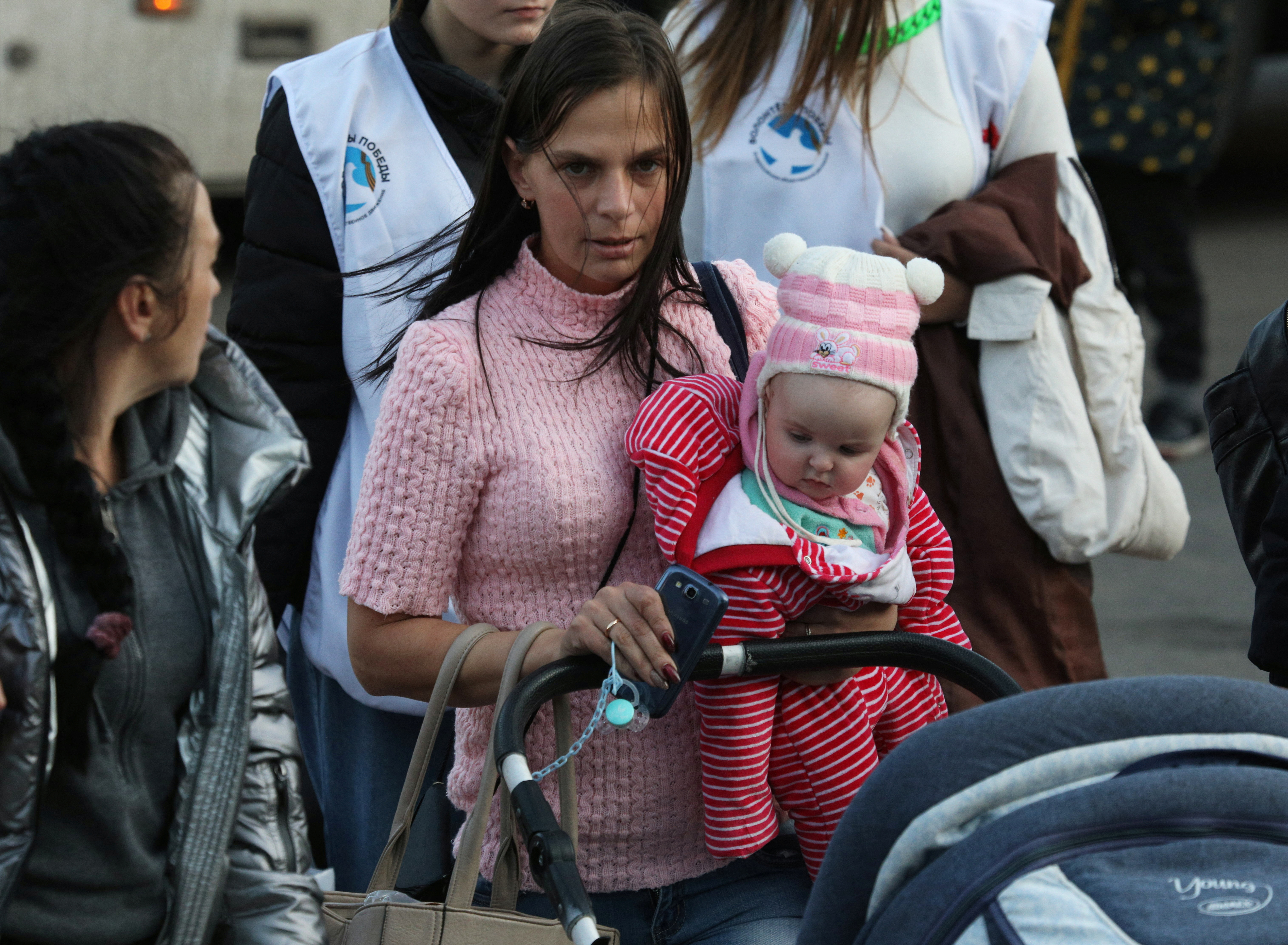 Una donna tiene in braccio un bambino mentre i civili sfollati dalla regione ucraina di Kherson, controllata dalla Russia, arrivano a una stazione ferroviaria locale, dopo che i funzionari russi hanno esteso un ordine di evacuazione all'area lungo la sponda orientale del fiume Dnipro, nella città di Dzhankoy, in Crimea .  2 novembre 2022. (Reuters) / Alexei Pavlichak