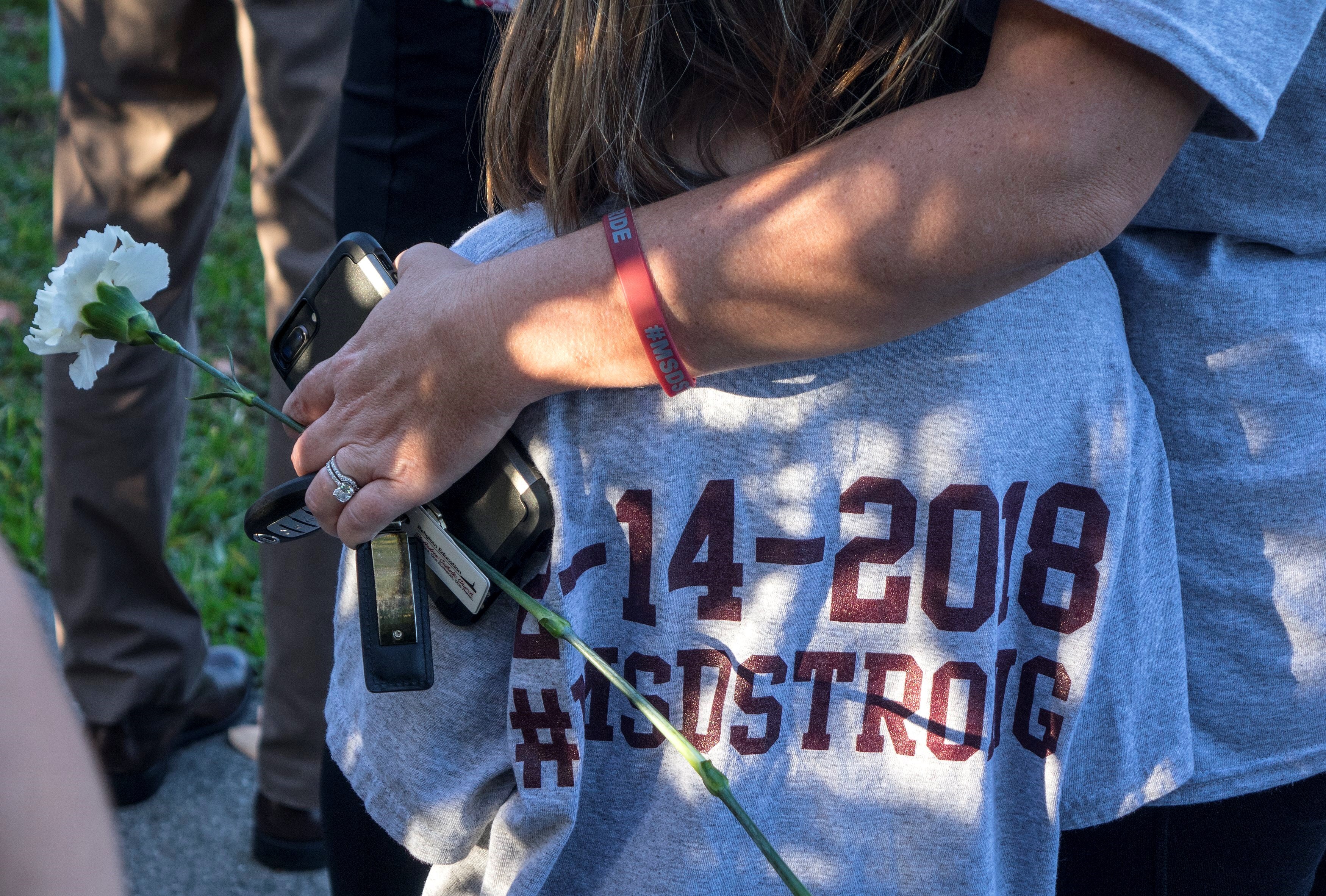 Fotografía de archivo, tomada el 28 de febrero de 2018, en la que se registró a una madre al abrazar a su hija, familiares de una joven que murió en la masacre de la escuela Marjory Stoneman Douglas, perpetrada catorce días antes por el joven Nikolas Cruz, en Parkland (Florida, EE.UU.). EFE/Cristóbal Herrera