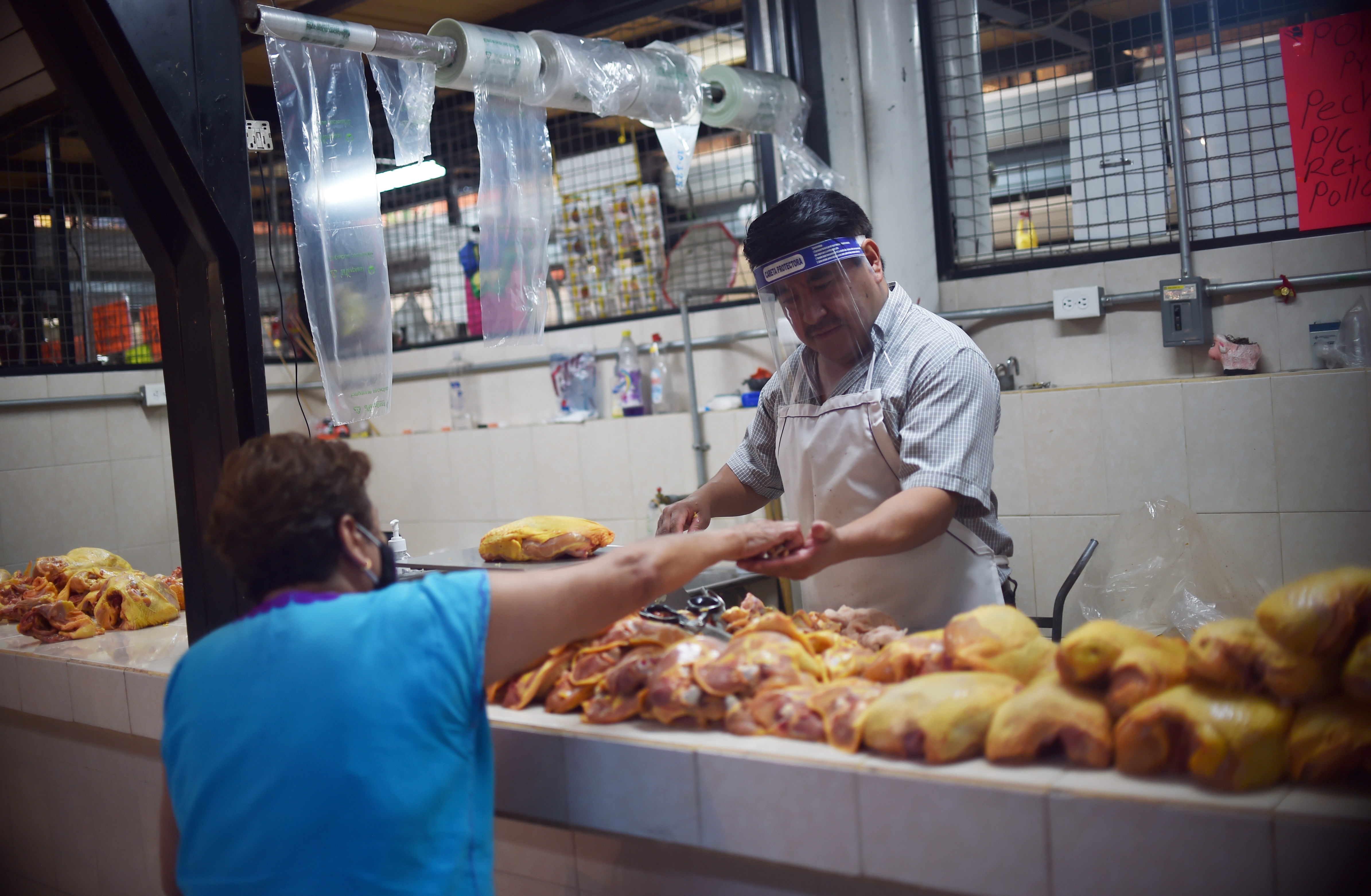 Un vendedor de pollo atiende a un cliente en un mercado popular en la Ciudad de México el 29 de junio de 2020. (Foto: RODRIGO ARANGUA / AFP)