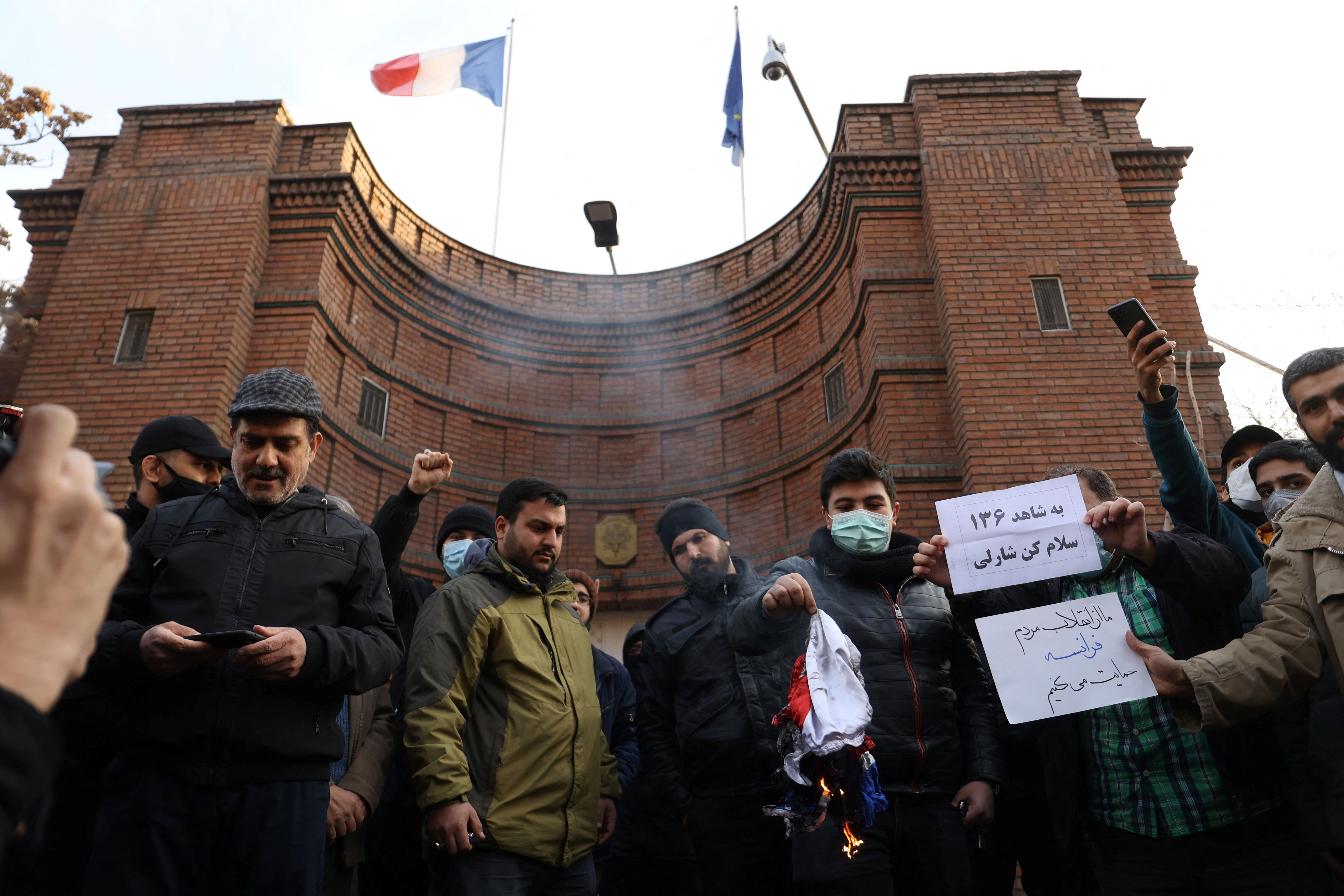 Manifestantes queman una bandera francesa durante una protesta para condenar a la revista francesa Charlie Hebdo (Majid Asgaripour/WANA vía REUTERS)