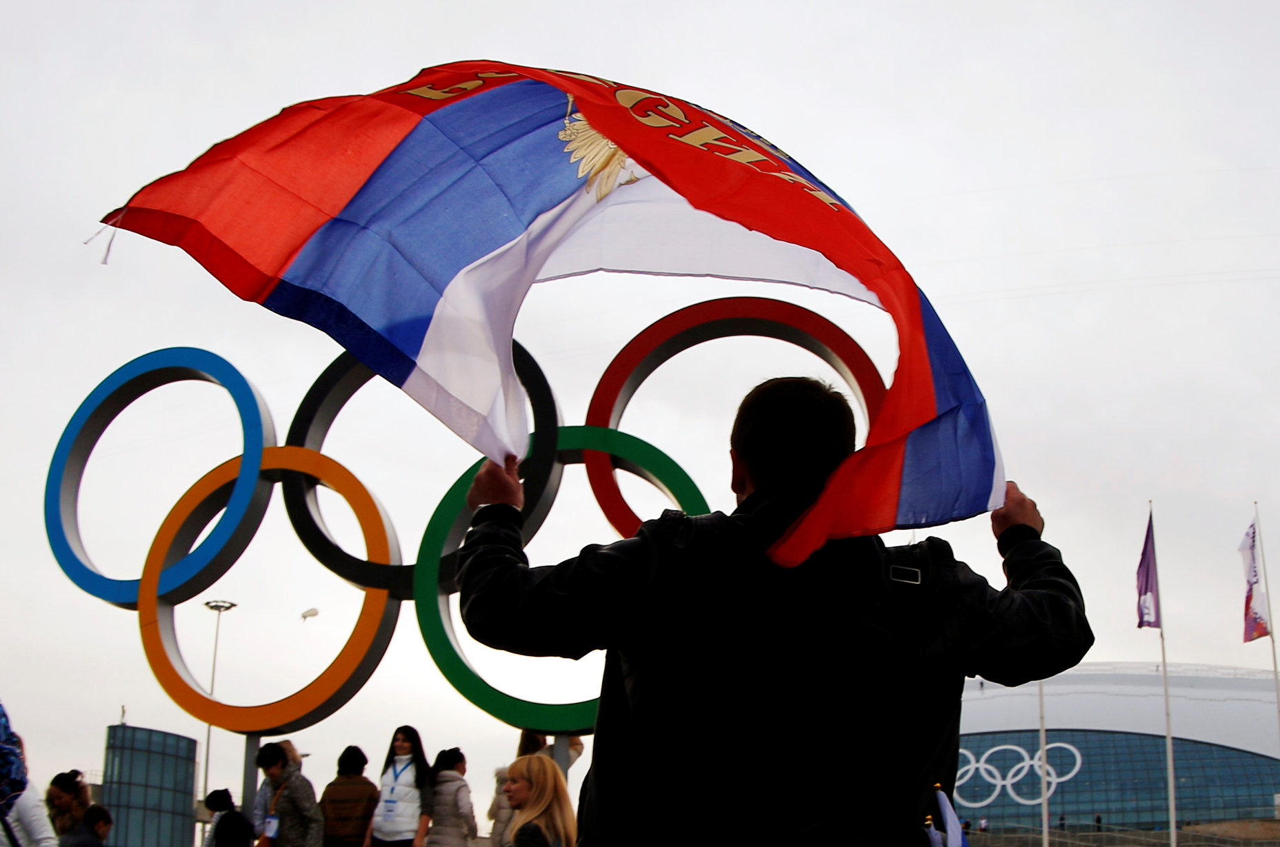 FILE PHOTO: A man carries the Russian flag past the Olympic rings at the Olympic Park during the 2014 Sochi Winter Olympics February 22, 2014. World Anti-Doping Agency has banned on December 9, 2019 Russian athletes from all major sporting events in the next four years.  REUTERS/Brian Snyder/File Photo