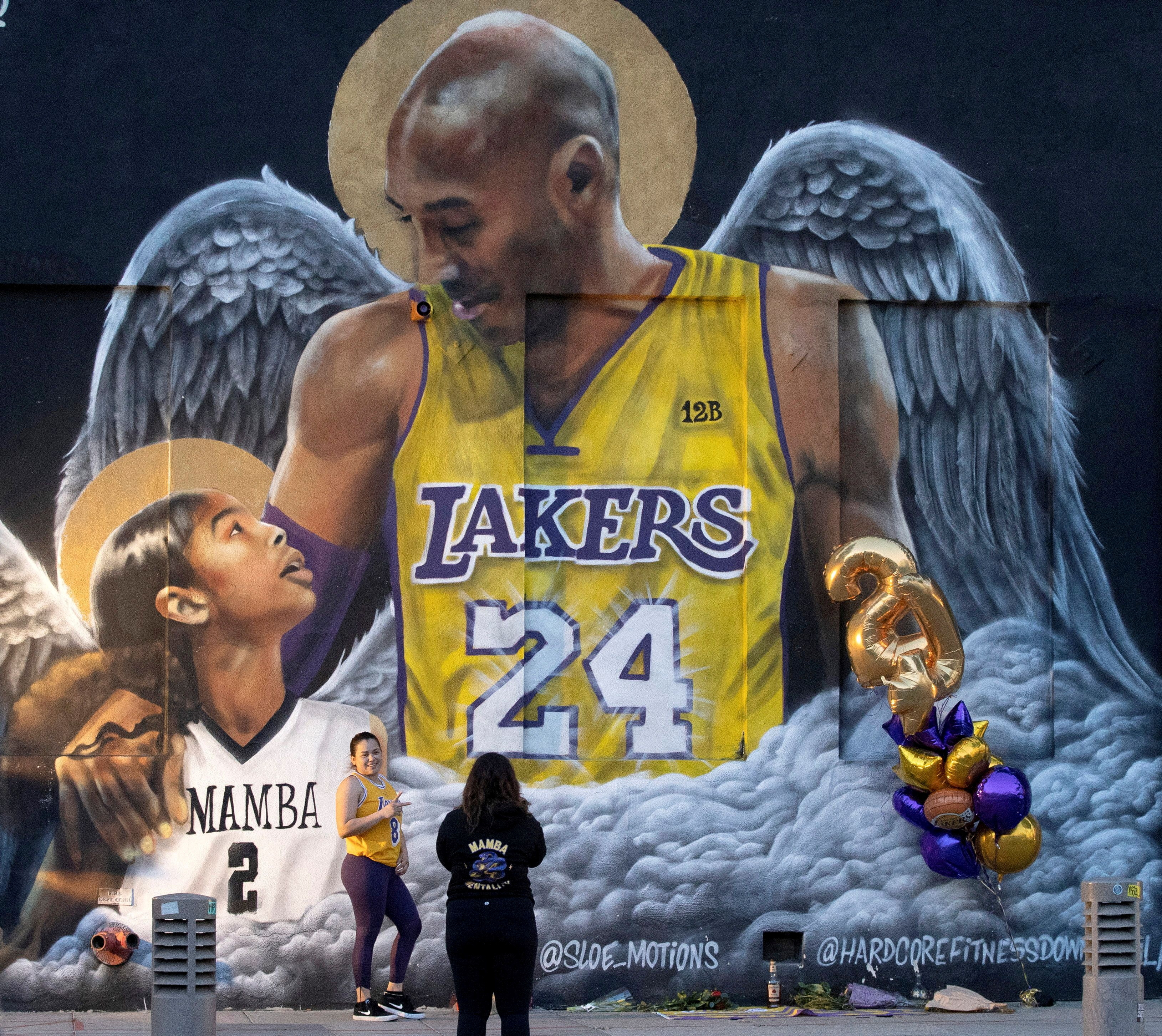 Un fan posa junto a un mural del fallecido Kobe Bryant, que pereció junto a su hija y otras siete personas cuando su helicóptero se estrelló contra una ladera, en Los Ángeles, California, Estados Unidos, 26 de enero de 2021. REUTERS/Mario Anzuoni/Archivo