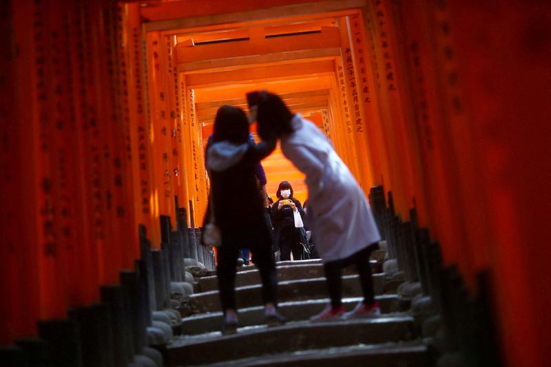 FOTO DE ARCHIVO. Visitantes, con mascarillas tras el brote de la enfermedad del coronavirus (COVID-19), exploran las puertas torii de madera del santuario sintoísta Fushimi Inari Taisha en Kioto, Japón. 13 de marzo de 2020. REUTERS/Edgard Garrido
