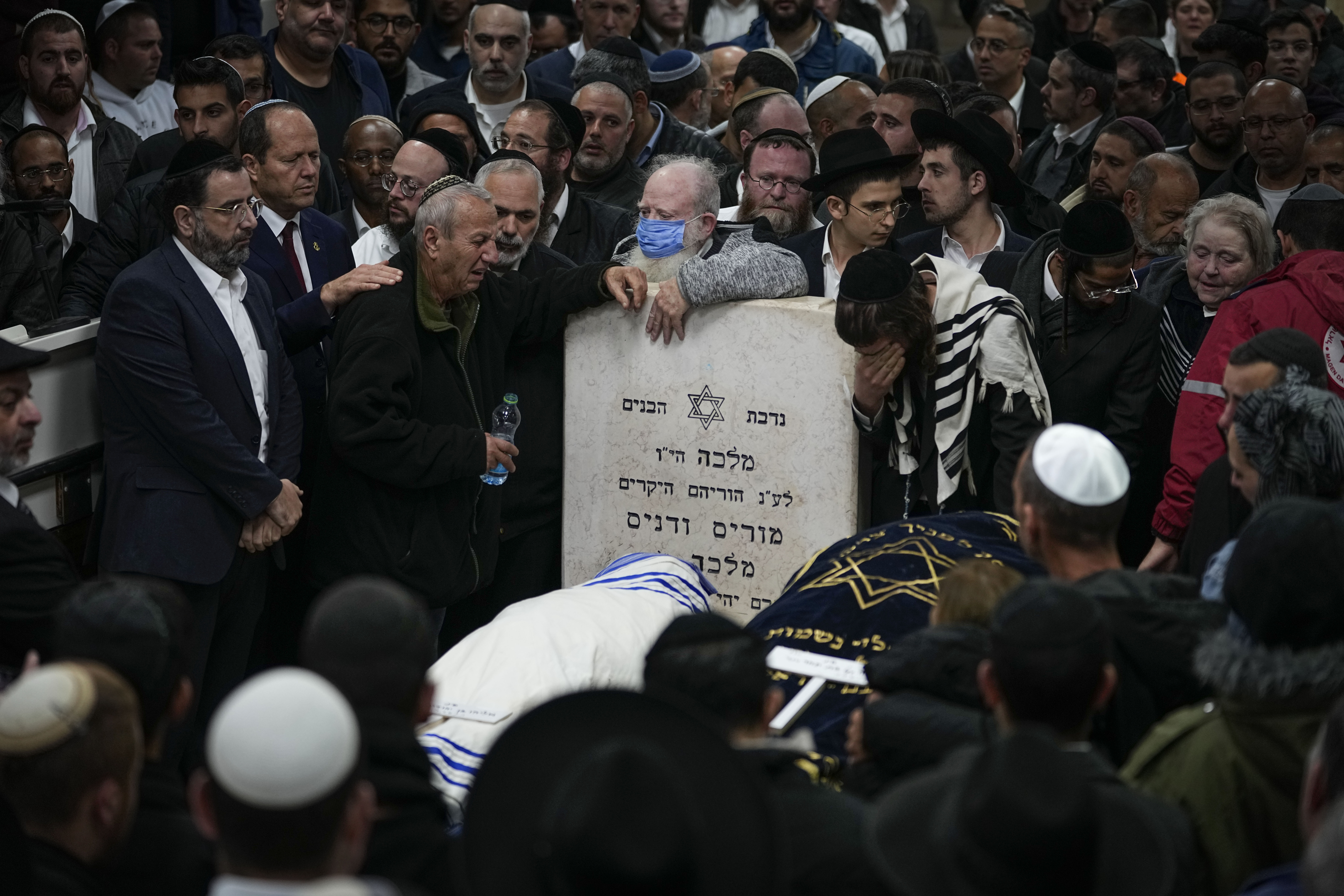 Dolientes en el funeral de los israleíes Eli Mizrahi y su esposa, Natalie, víctimas de un ataque el último viernes en Jerusalén, en el cementerio de Beit Shemesh, Israel, la mañana del domingo 29 de enero de 2023. (AP Foto/Ariel Schalit)