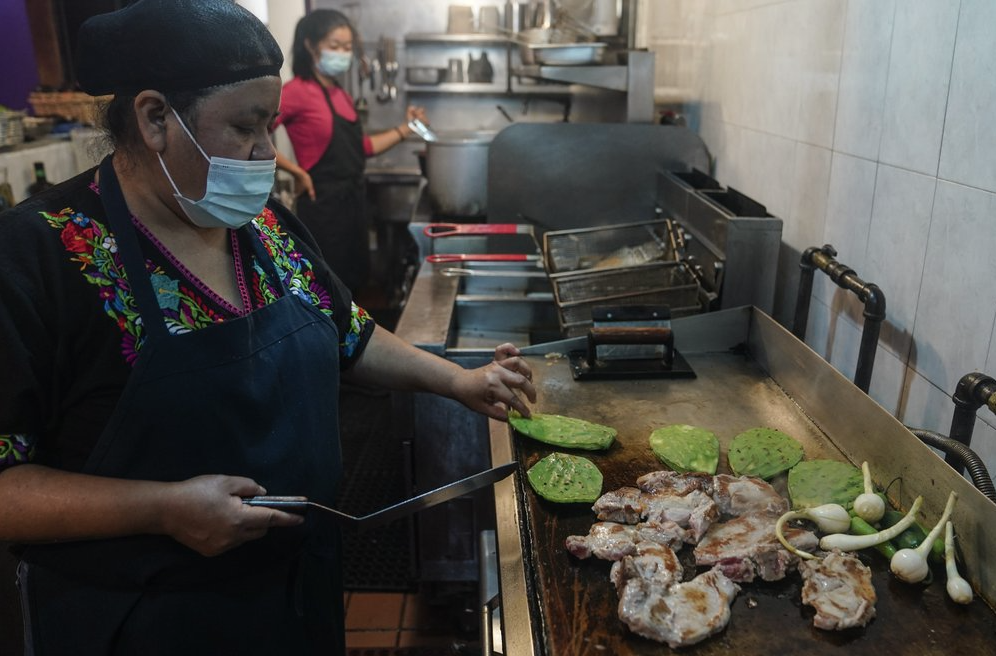 Natalia Méndez prepara una comida con chuletas de cerdo, jalapeños y nopales en la cocina de La Morada, un restaurante mexicano galardonado del que es copropietaria con su familia en el sur del Bronx, el miércoles 28 de octubre de 2020, en Nueva York (AP Foto/Bebeto Matthews)