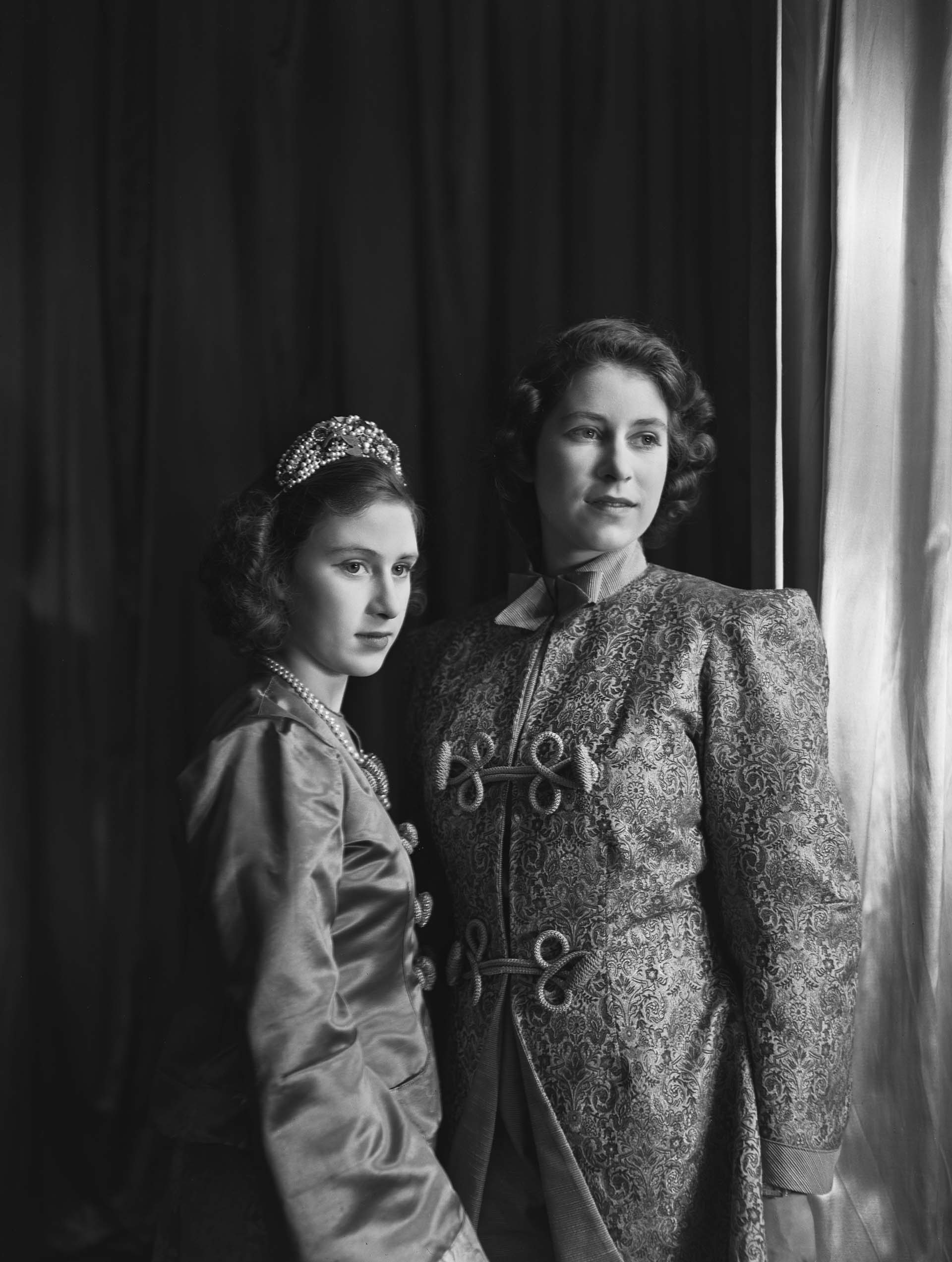 La Princesa Isabel (Reina Isabel II) y la Princesa Margarita (1930-2002), ambas en traje, fotografiadas antes de una producción de pantomima real de "Aladino" en el Castillo de Windsor, Berkshire, Gran Bretaña, 15 de diciembre de 1943. (Photo by Lisa Sheridan/Studio Lisa/Getty Images)