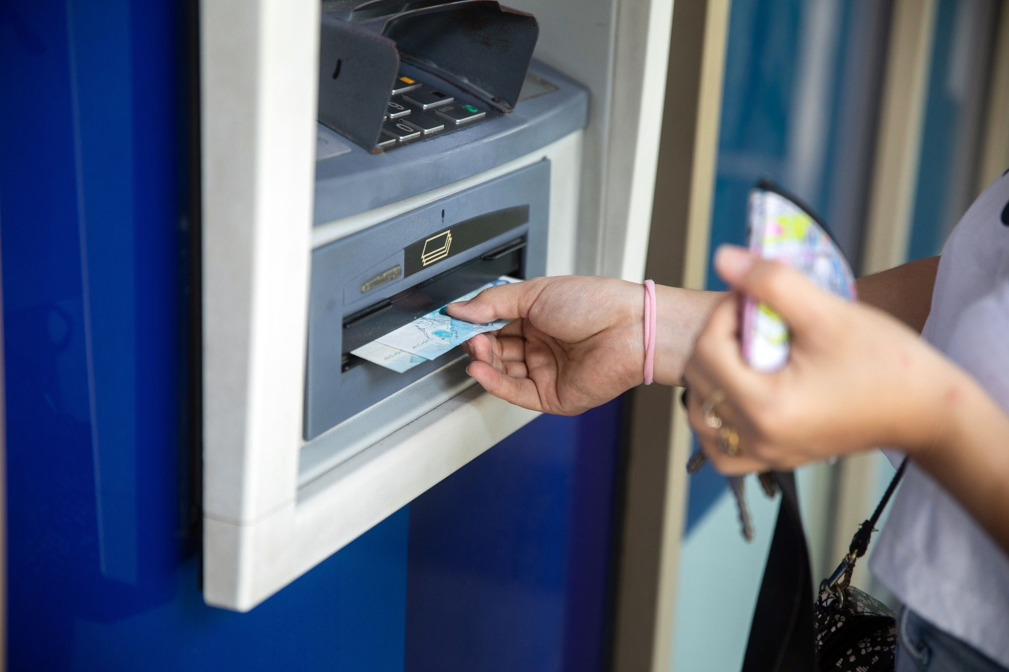Un cliente retira billetes de un cajero automático