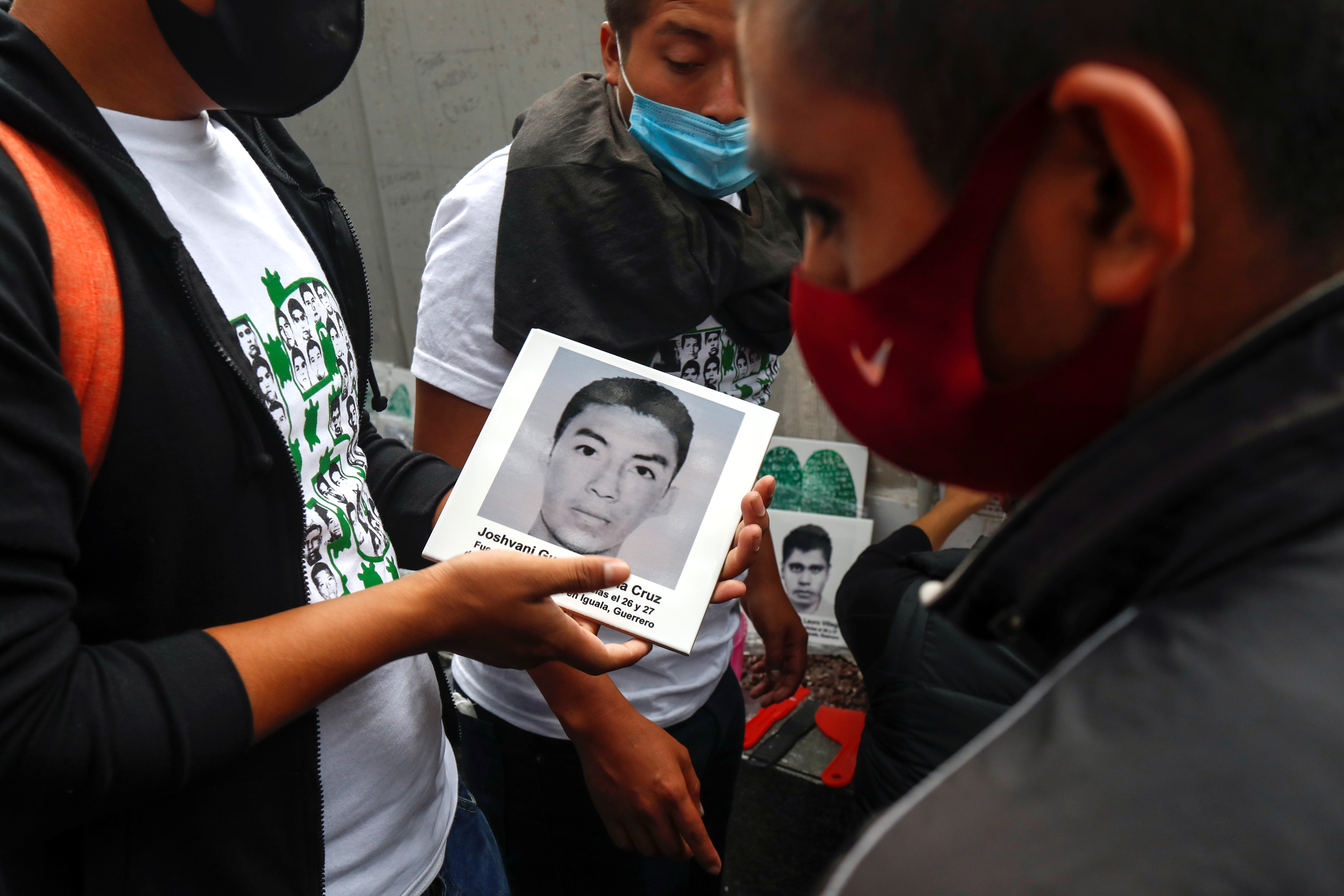 Un hombre sostiene una cerámica con la imagen de uno de los estudiantes desaparecidos, mientras la gente participa en una protesta frente a la Fiscalía General, antes del sexto aniversario de la desaparición de 43 estudiantes de la Escuela Normal Rural de Ayotzinapa, en la Ciudad de México. México 25 de septiembre de 2020.