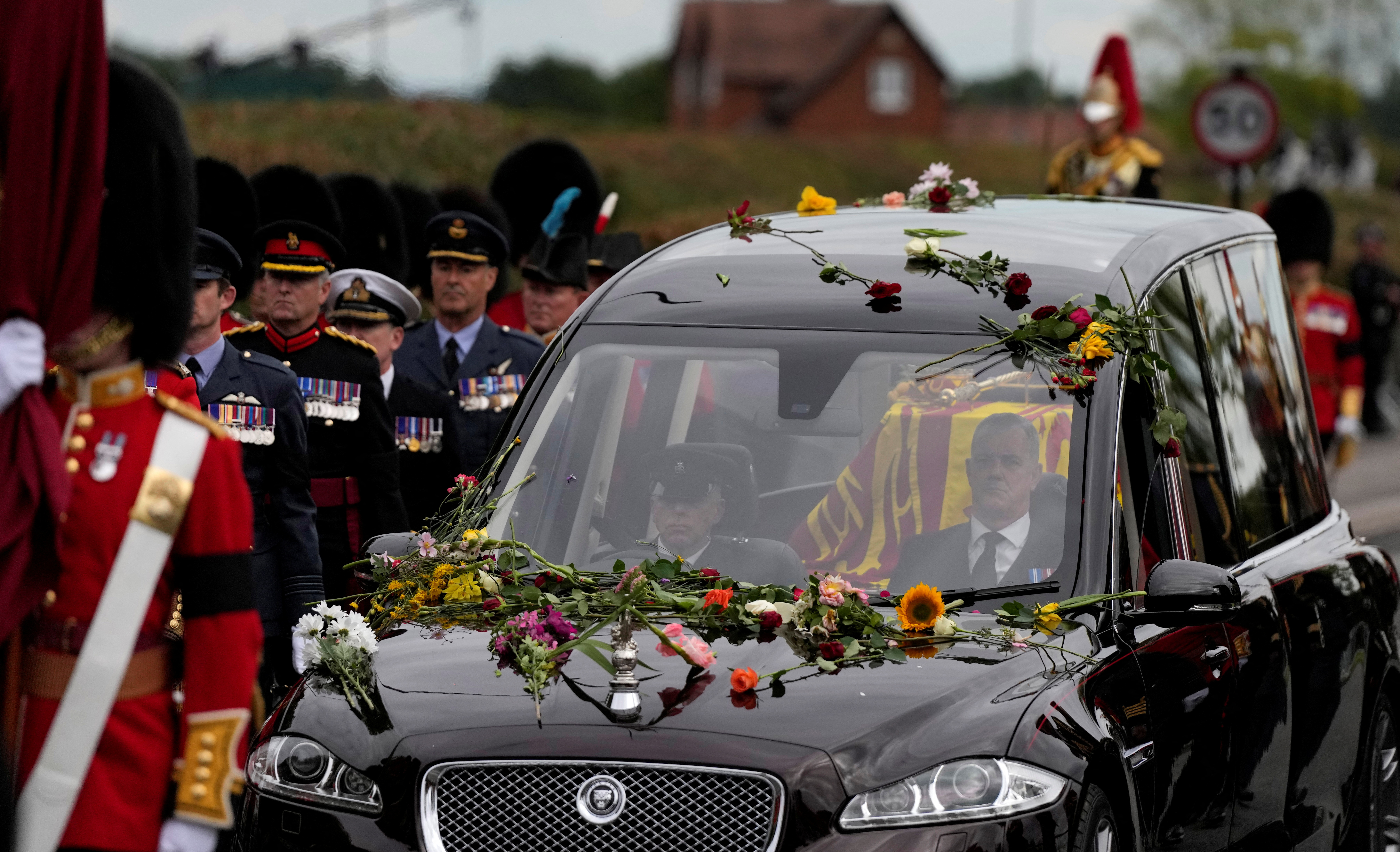 Flowers cover the hearse carrying the coffin of Queen Elizabeth II as it arrives on the Albert Road outside Windsor Castle in Windsor, England, Monday, Sept. 19, 2022. The Queen, who died aged 96 on Sept. 8, will be buried at Windsor alongside her late husband, Prince Philip, who died last year. Alastair Grant/Pool via REUTERS