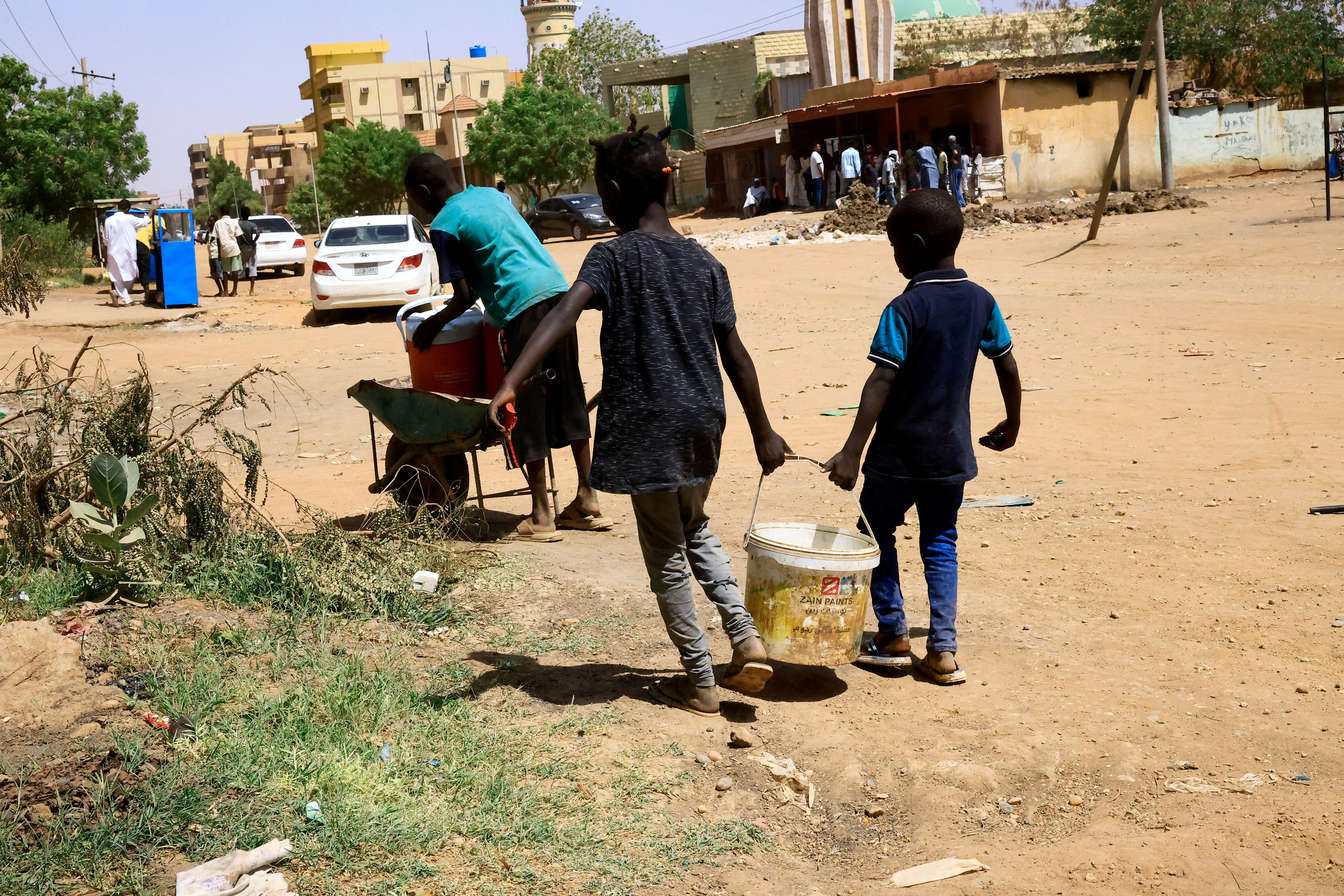 Niños llevan un cubo de agua durante los enfrentamientos entre las Fuerzas de Apoyo Rápido paramilitares y el ejército en Jartum Norte, Sudán, 22 de abril de 2023. REUTERS/Mohamed Nureldin Abdallah