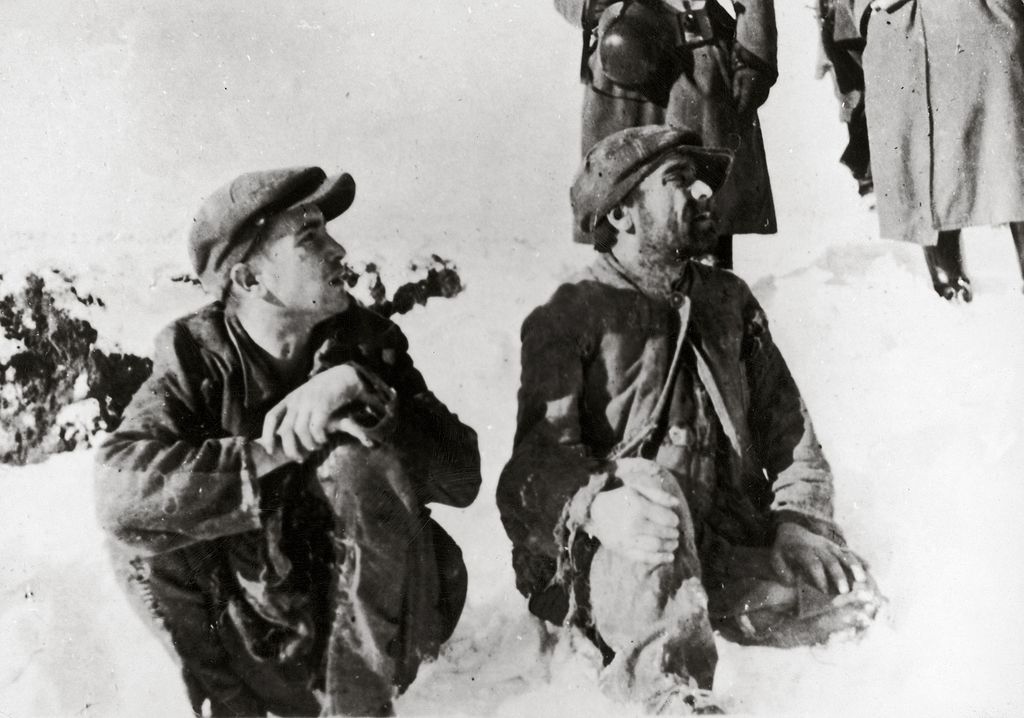 Dos judíos polacos sentando en la nieve antes de ser asesinados, en el fondo los soldados alemanes (Imagno/Getty Images)