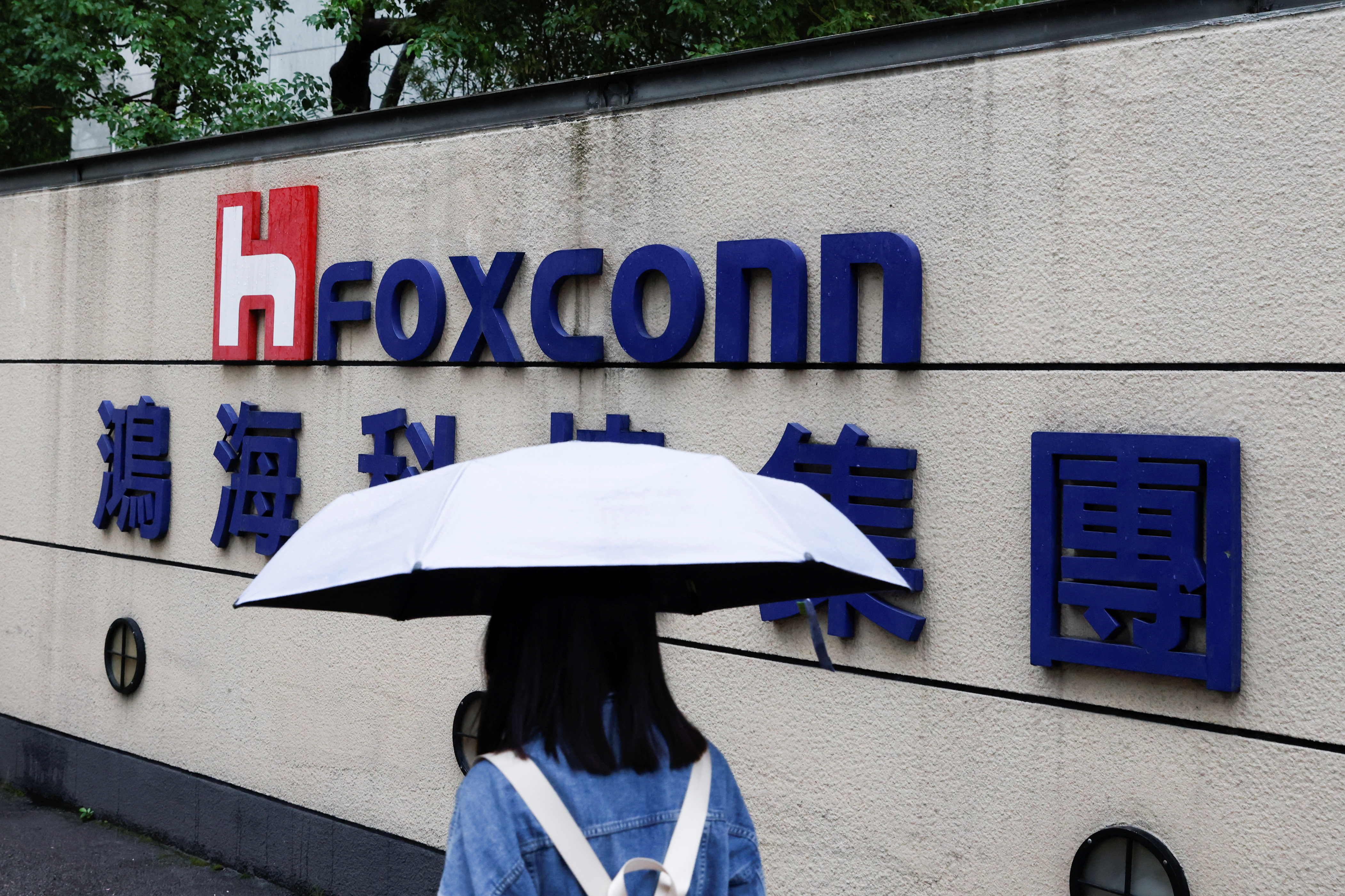 Una mujer que lleva un paraguas pasa junto al logo de Foxconn frente al edificio de una empresa en Taipei, Taiwán, el 31 de octubre de 2022. REUTERS/Carlos García Rawlins