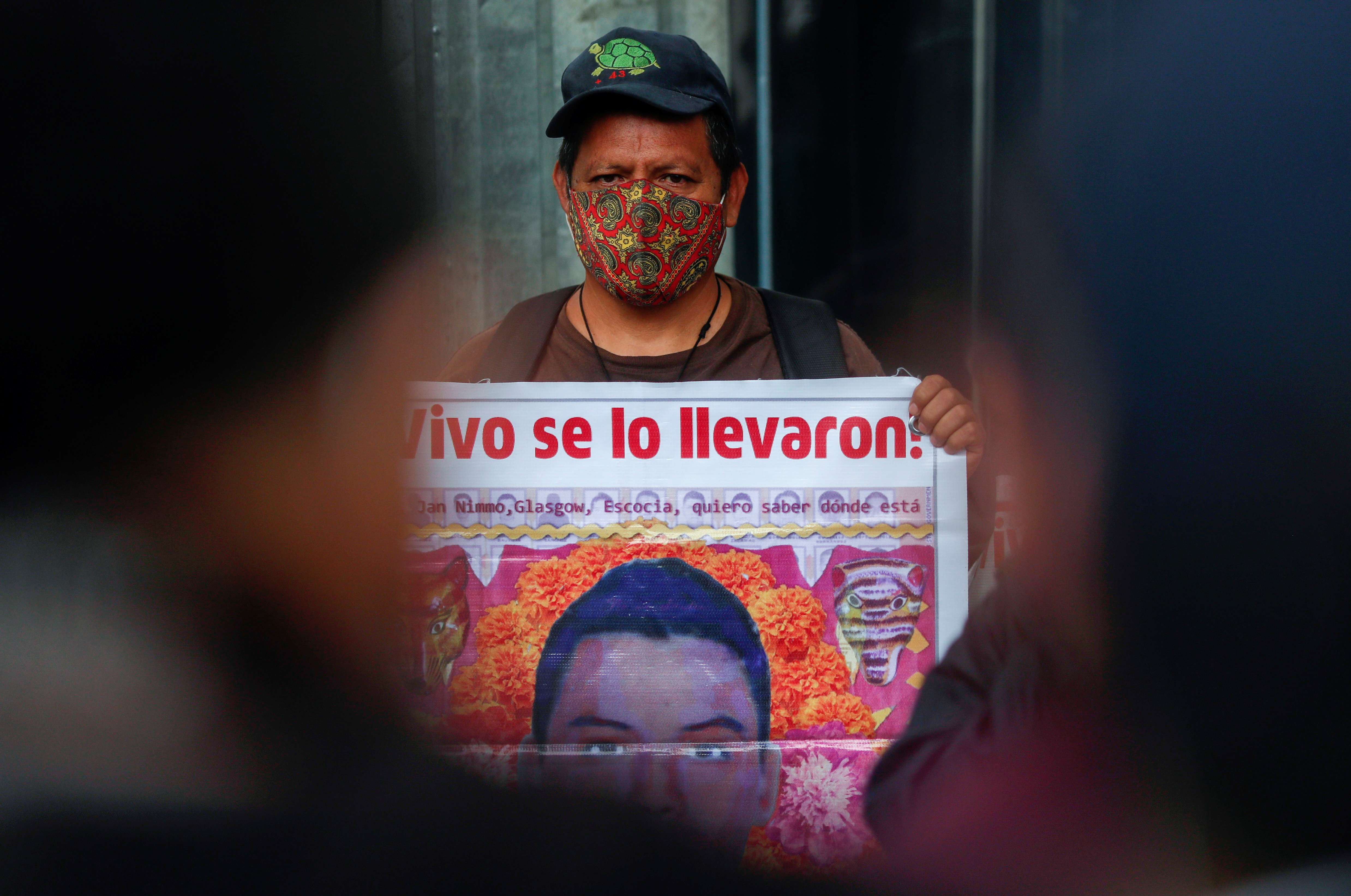 Un familiar de un estudiante desaparecido sostiene un cartel con su imagen mientras participa en una protesta frente a la Fiscalía General de la República, antes del sexto aniversario de la desaparición de 43 estudiantes de la Facultad de Formación de Maestros de Ayotzinapa, en la Ciudad de México, México 25 de septiembre, 2020.