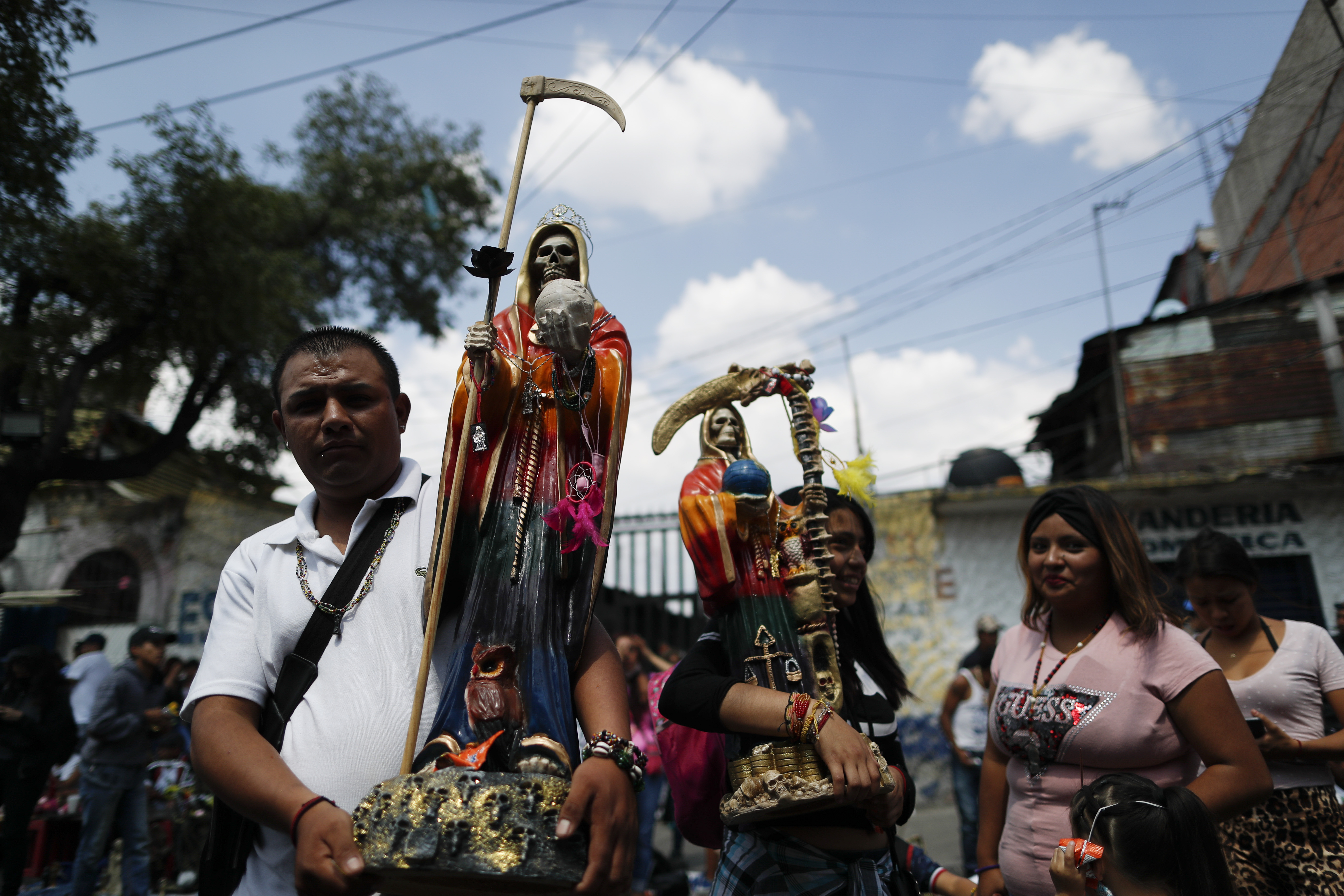 Los devotos llevan estatuas de la Santa Muerte mientras esperan en la fila para presentar sus respetos en su altar en el barrio de Tepito, Ciudad de México, el lunes 1 de junio de 2020. (Foto: AP / Rebecca Blackwell)