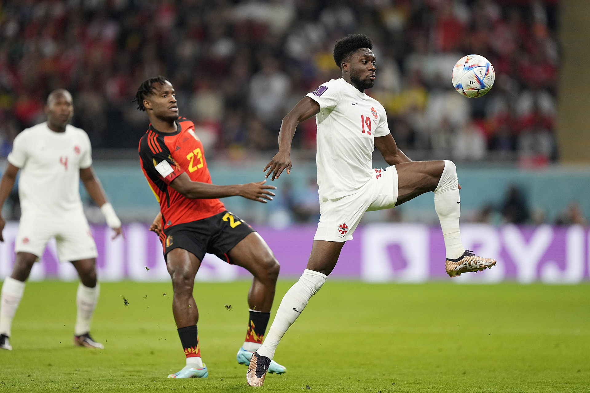 Alphonso Davies controla la pelota ante la marca de Michy Batshuayi en el encuentro entre Bélgica y Canadá (AP Photo/Martin Meissner)
