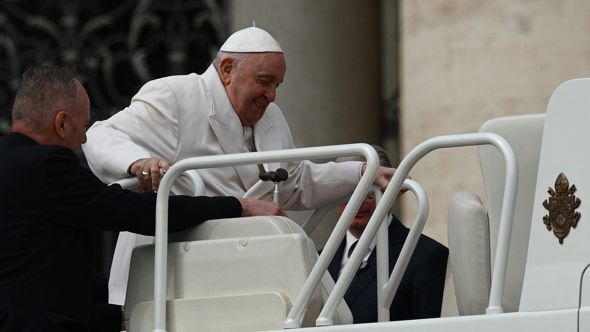 El Papa Francisco es ayudado a subir al papamóvil (Photo by Vincenzo PINTO / AFP)