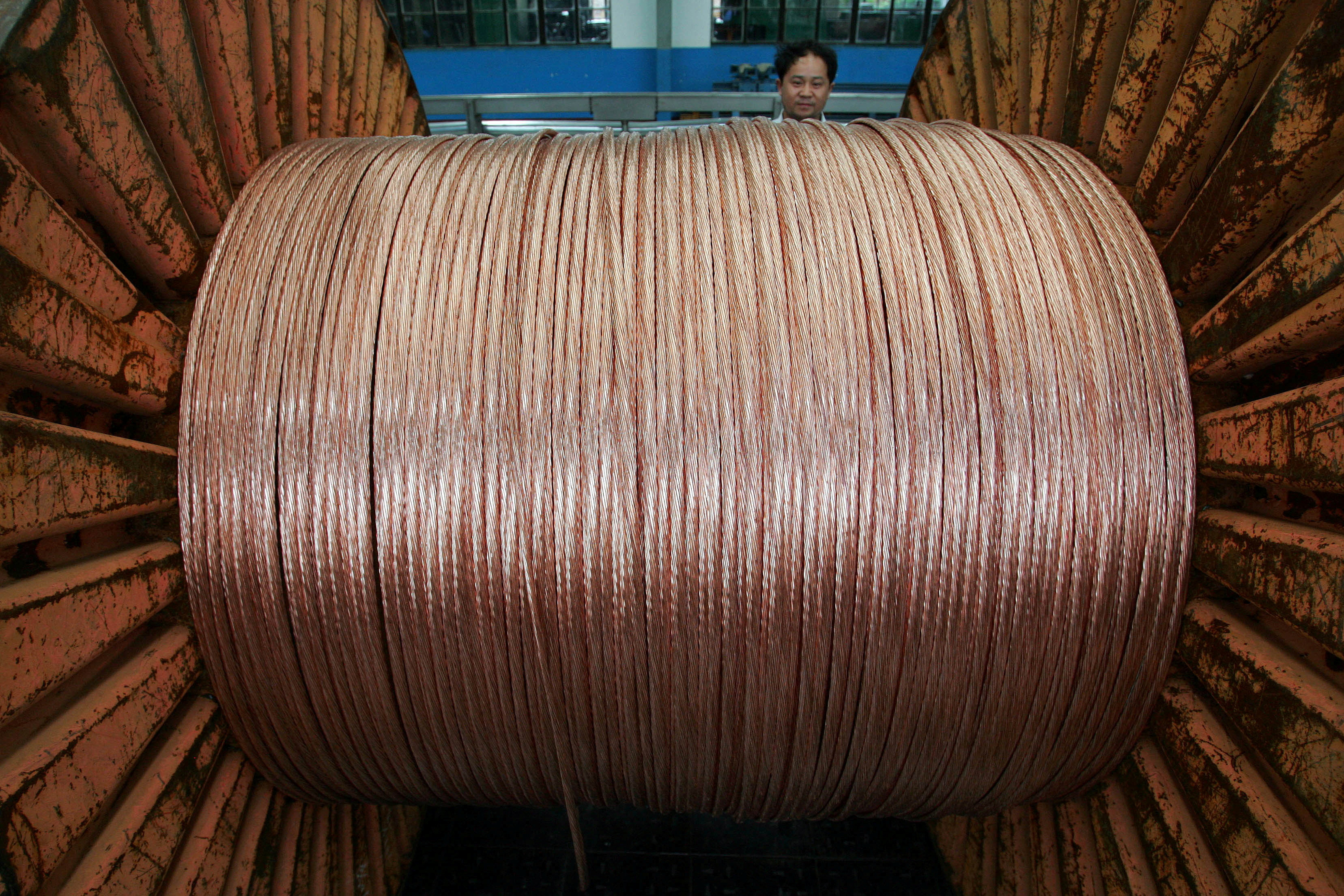 Un trabajador chino detrás de un rollo de alambre de cobre, de importancia clave en la transición energética