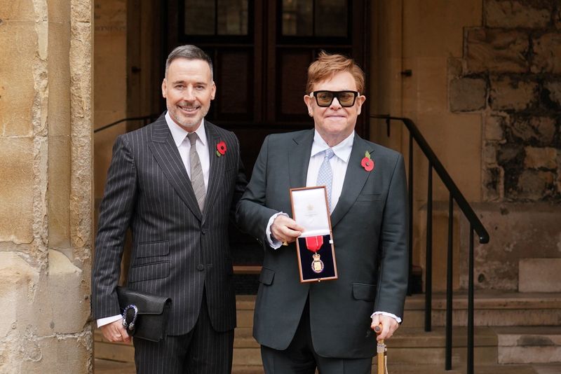 El músico Elton John junto a su marido David Furnish, tras ser nombrado miembro de la Orden de los Compañeros de Honor por sus servicios a la música y a la caridad durante una ceremonia de investidura en el Castillo de Windsor, en Gran Bretaña, el 10 de noviembre de 2021 (REUTERS)