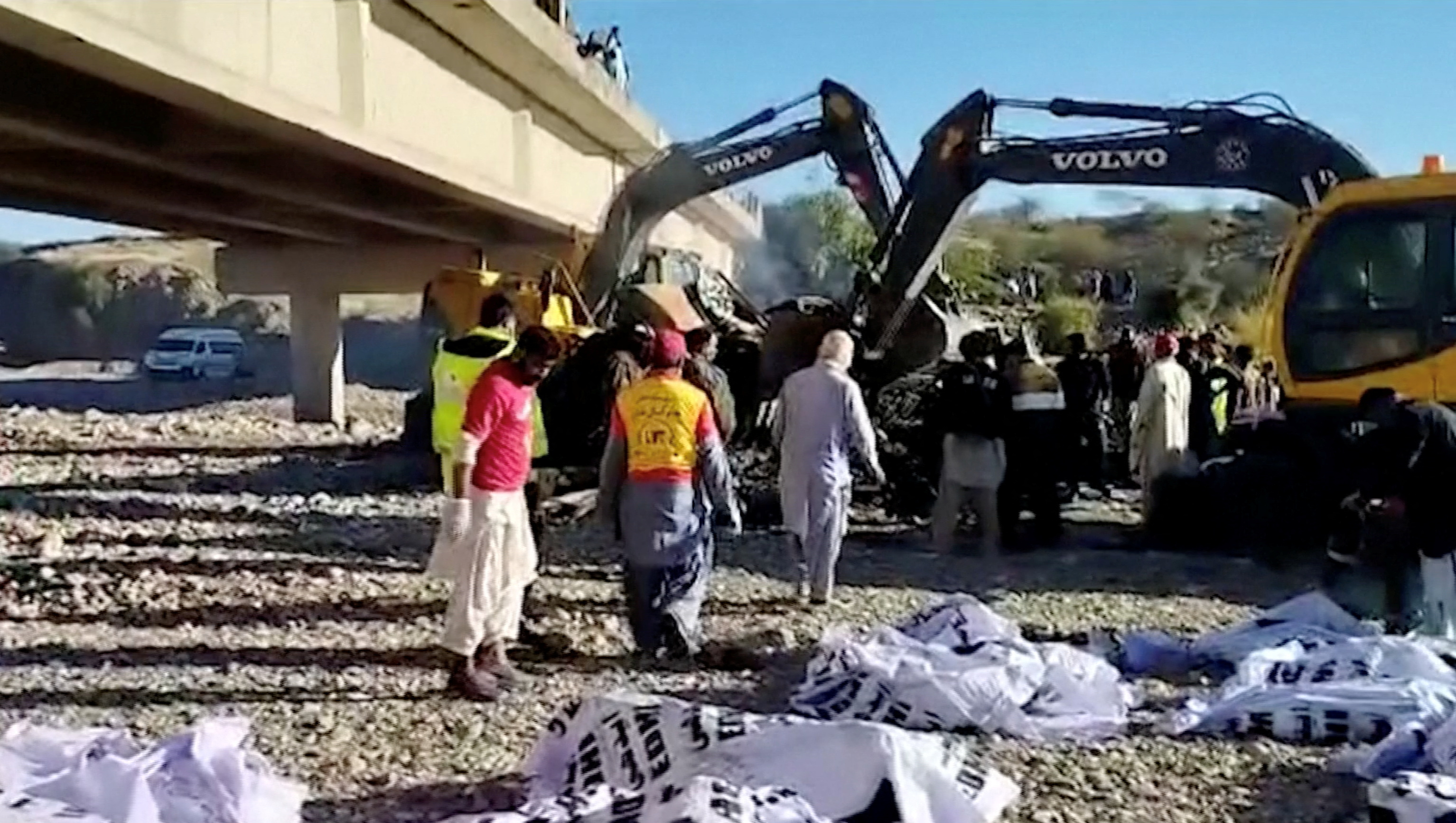 Los cuerpos de las víctimas yacen en bolsas mientras la gente trabaja en el lugar de un accidente de autobús en el distrito de Lasbela, provincia de Baluchistán (Reuters)