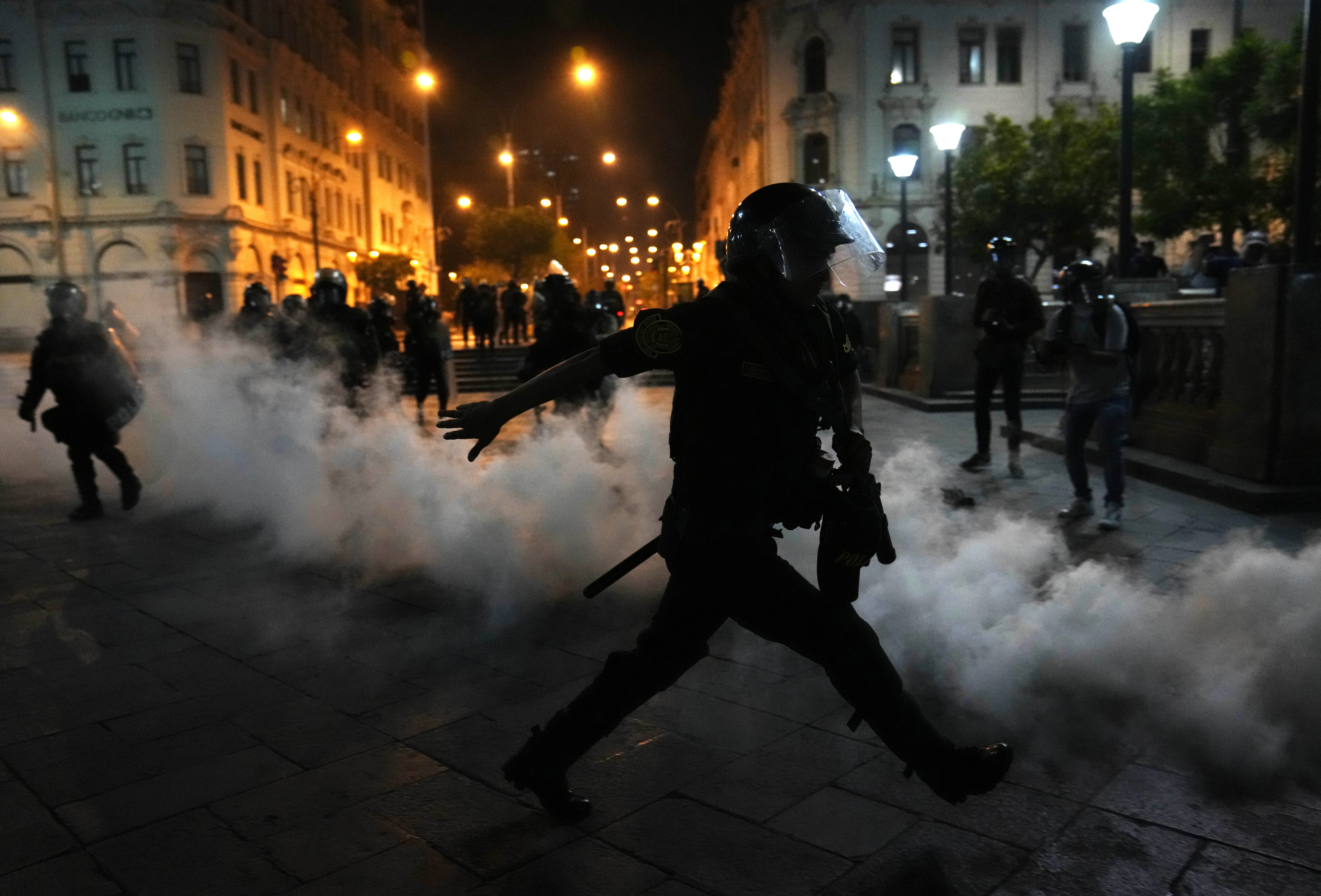 A cloud of tear gas surrounds police officers trying to disperse supporters of ousted President Pedro Castillo in San Martin Square, Lima, Sunday, Dec. 11, 2022.  (AP Photo/Martin Mejia)