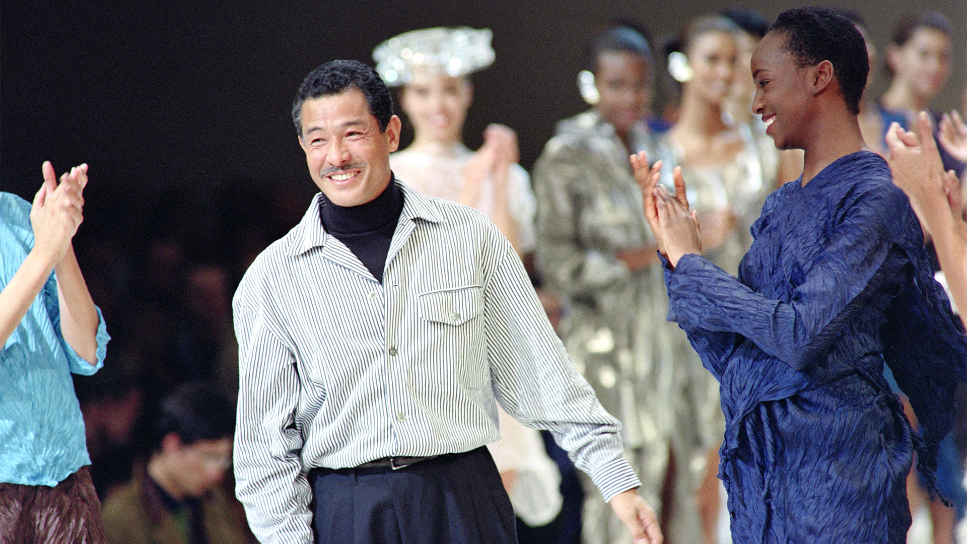 19 de octubre de 1991: Issey Miyake recibe aplausos de modelos y asistentes después de presentar su colección Primavera-Verano 1992 en París. (Foto de Pierre GUILLAUD / AFP)
