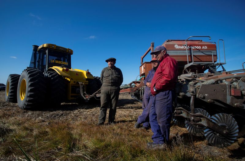 Stock Photo - Two agricultural workers chat before operating a tractor with a seeder in Comodoro Py, on the outskirts of Buenos Aires, Argentina.  June 21, 2022. REUTERS/Matias Baglietto