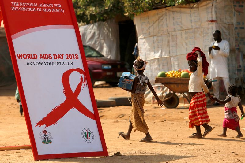 Niños pasan junto a una pancarta durante una campaña de sensibilización sobre el VIH/SIDA con motivo del Día Mundial del SIDA en el campamento de desplazados internos de Kuchingoro en Abuja, Nigeria. África es el continente más golpeado por esta pandemia (Reuters/ Afolabi Sotunde)