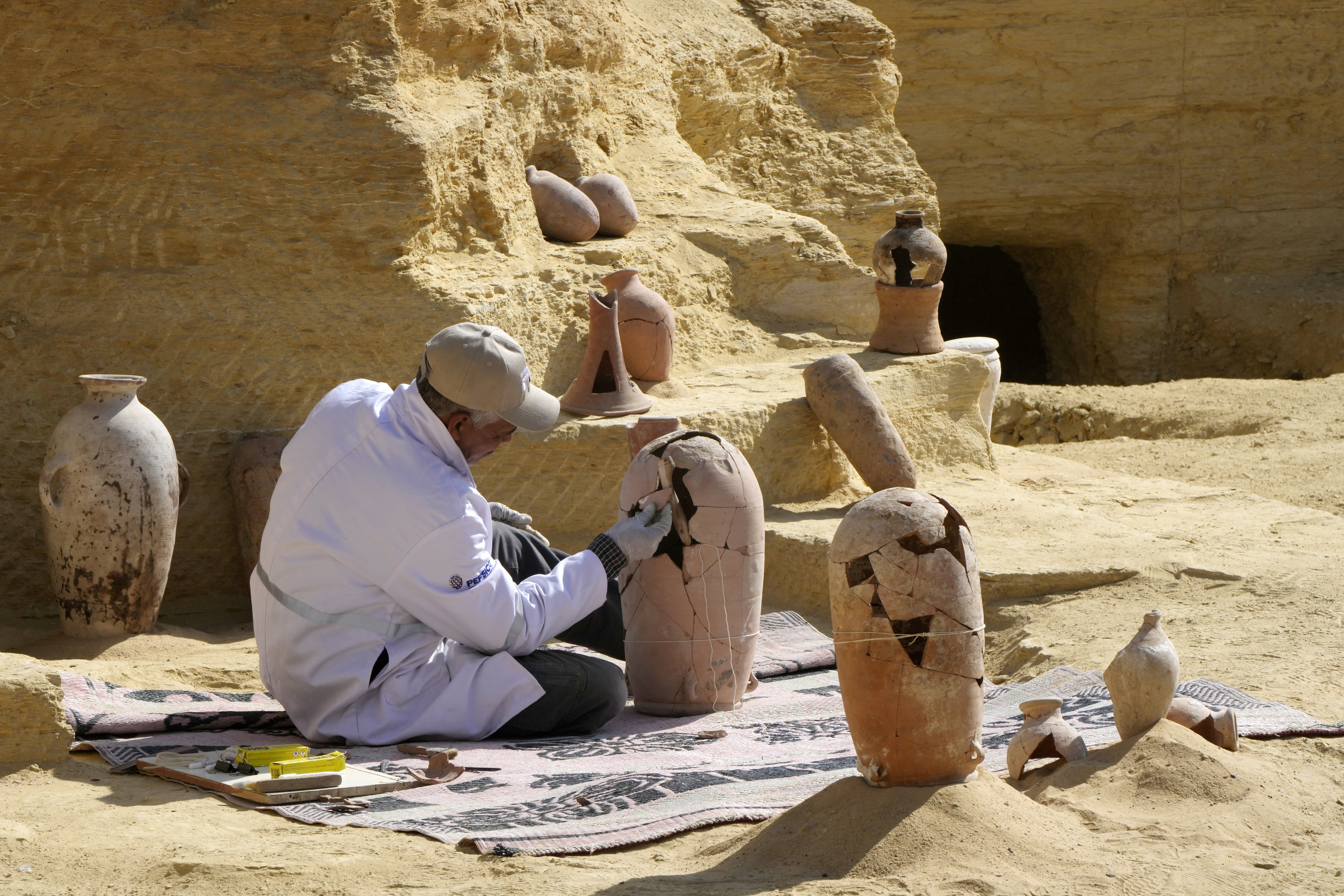 Un arqueólogo trabaja en la restauración de una vasija encontrada en el sitio (Foto AP/Amr Nabil)
