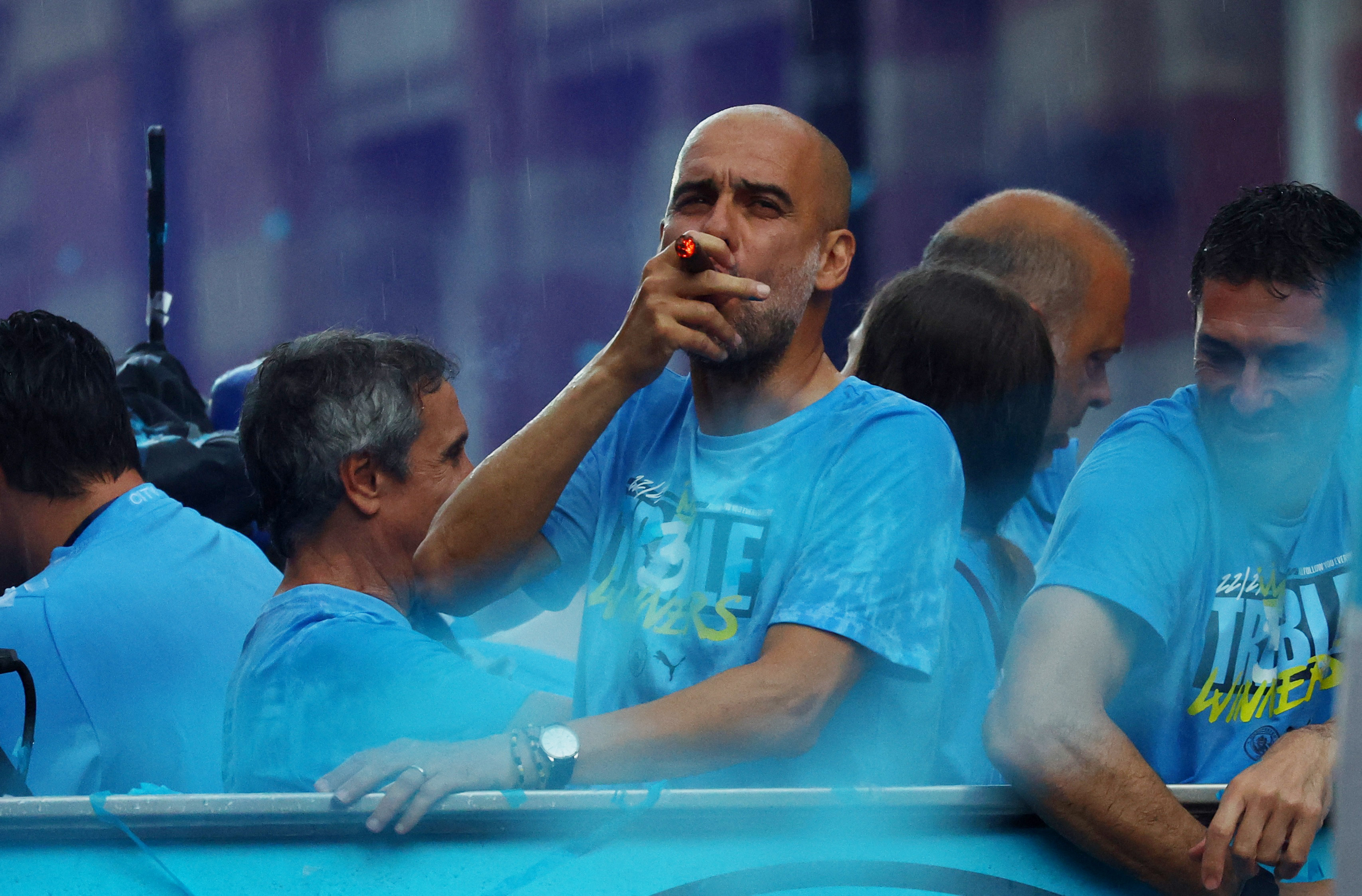 Soccer Football - Manchester City Victory Parade - Manchester, Britain - June 12, 2023 Manchester City manager Pep Guardiola is pictured smoking a cigar during the parade REUTERS/Molly Darlington