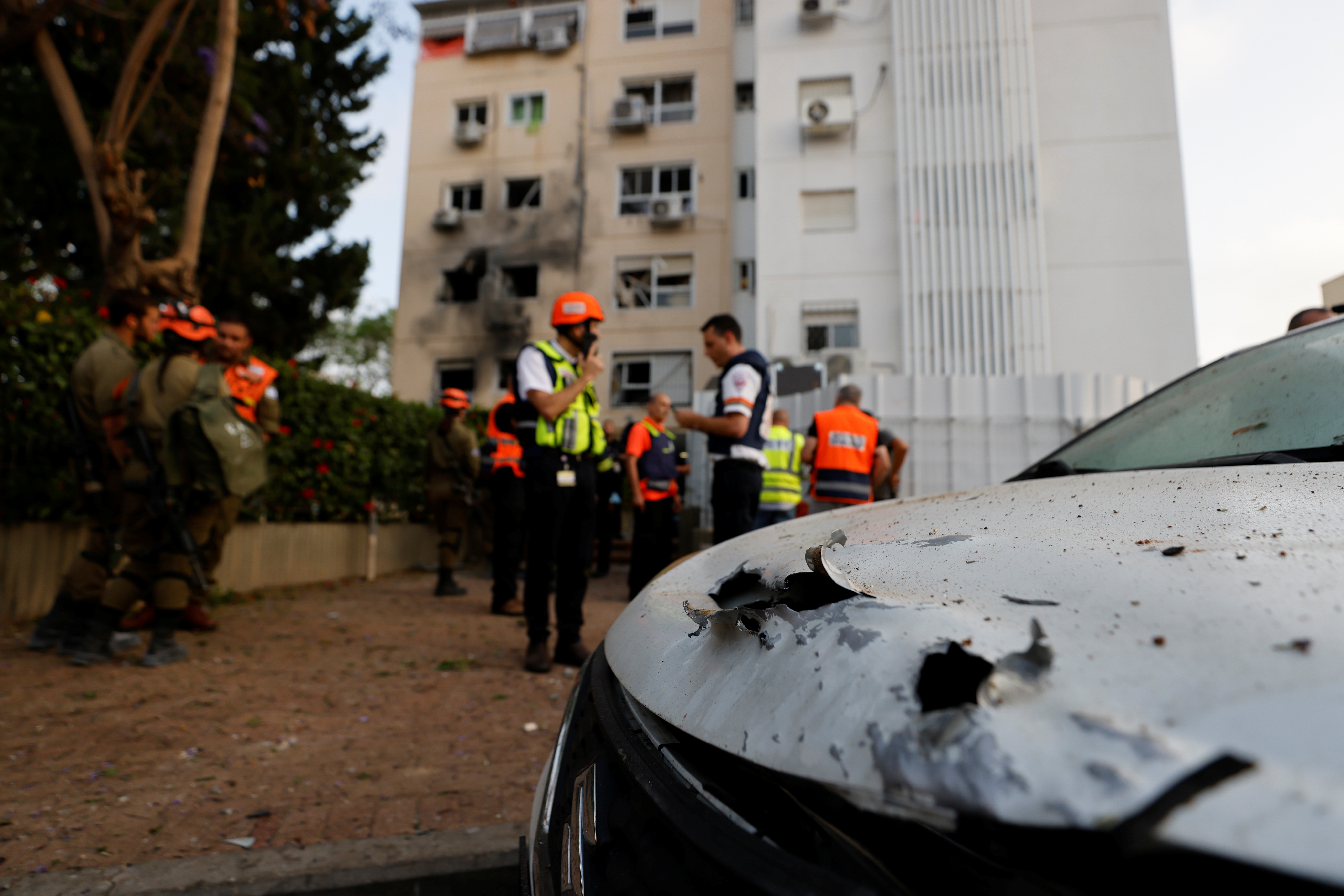Médicos y soldados israelíes parados cerca de un automóvil dañado después de que un cohete lanzado desde la Franja de Gaza golpeara un edificio residencial en Ashkelon, en el sur de Israel. REUTERS/Amir Cohen