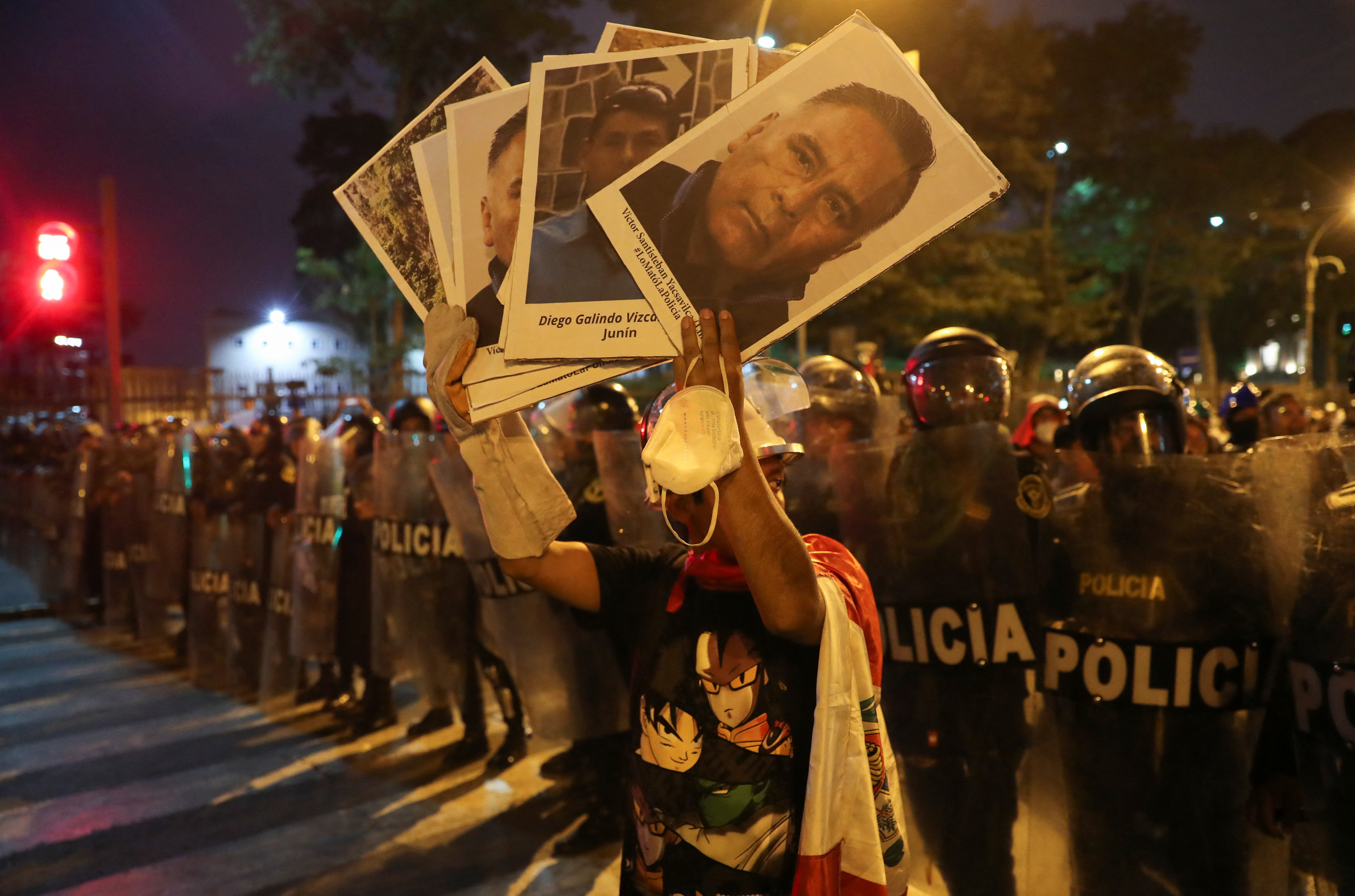 Un manifestante sostiene pancartas frente a policías durante una protesta en Lima, el 31 de enero. (REUTERS/Sebastian Castaneda)
