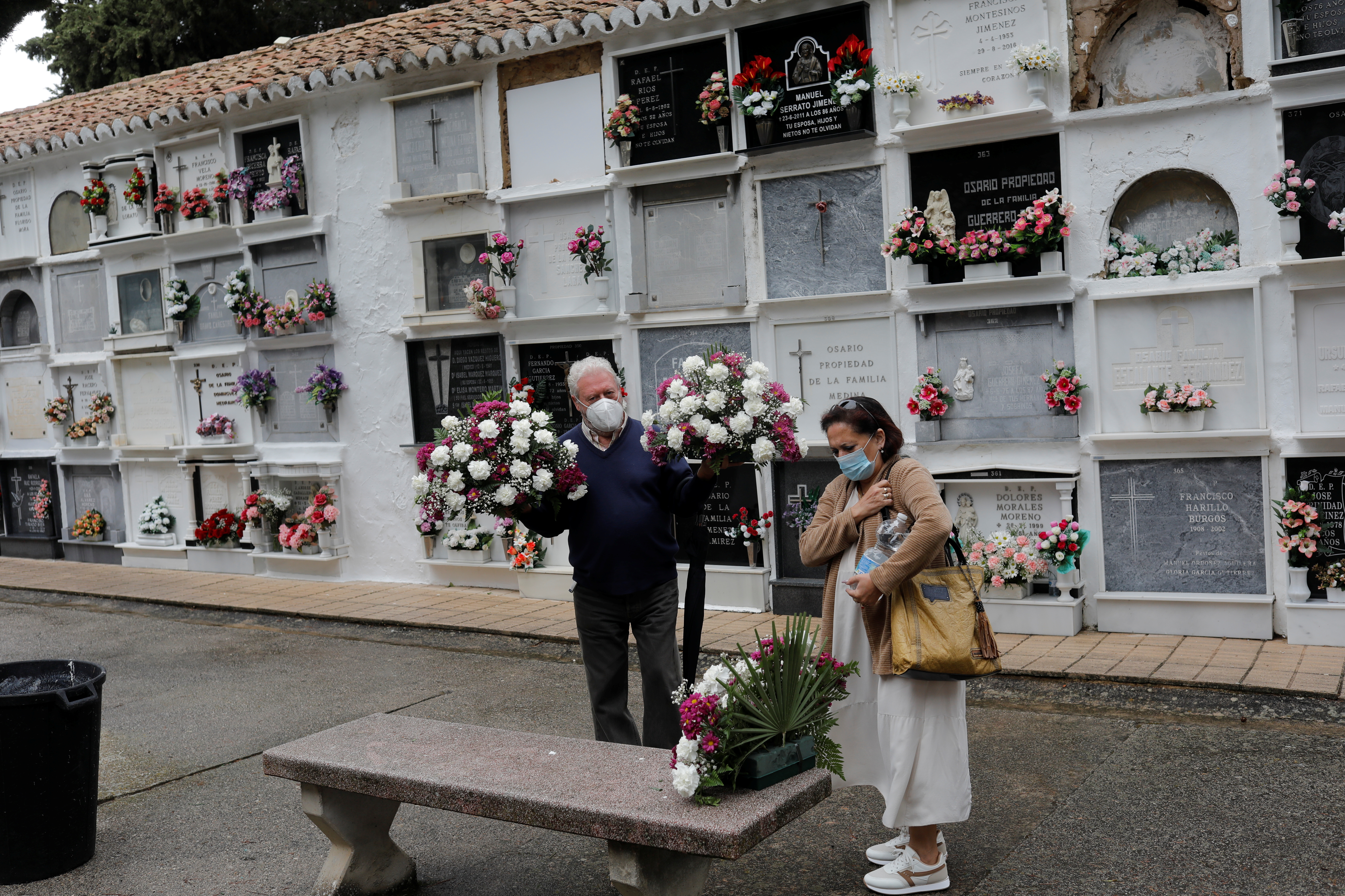 Personas llevan flores para colocarlas en la lápida de su familiar en un cementerio durante el Día de Todos los Santos, en medio de la pandemia de la enfermedad del coronavirus (COVID-19), en Ronda, España 1 de noviembre de 2021. REUTERS/Jon Nazca