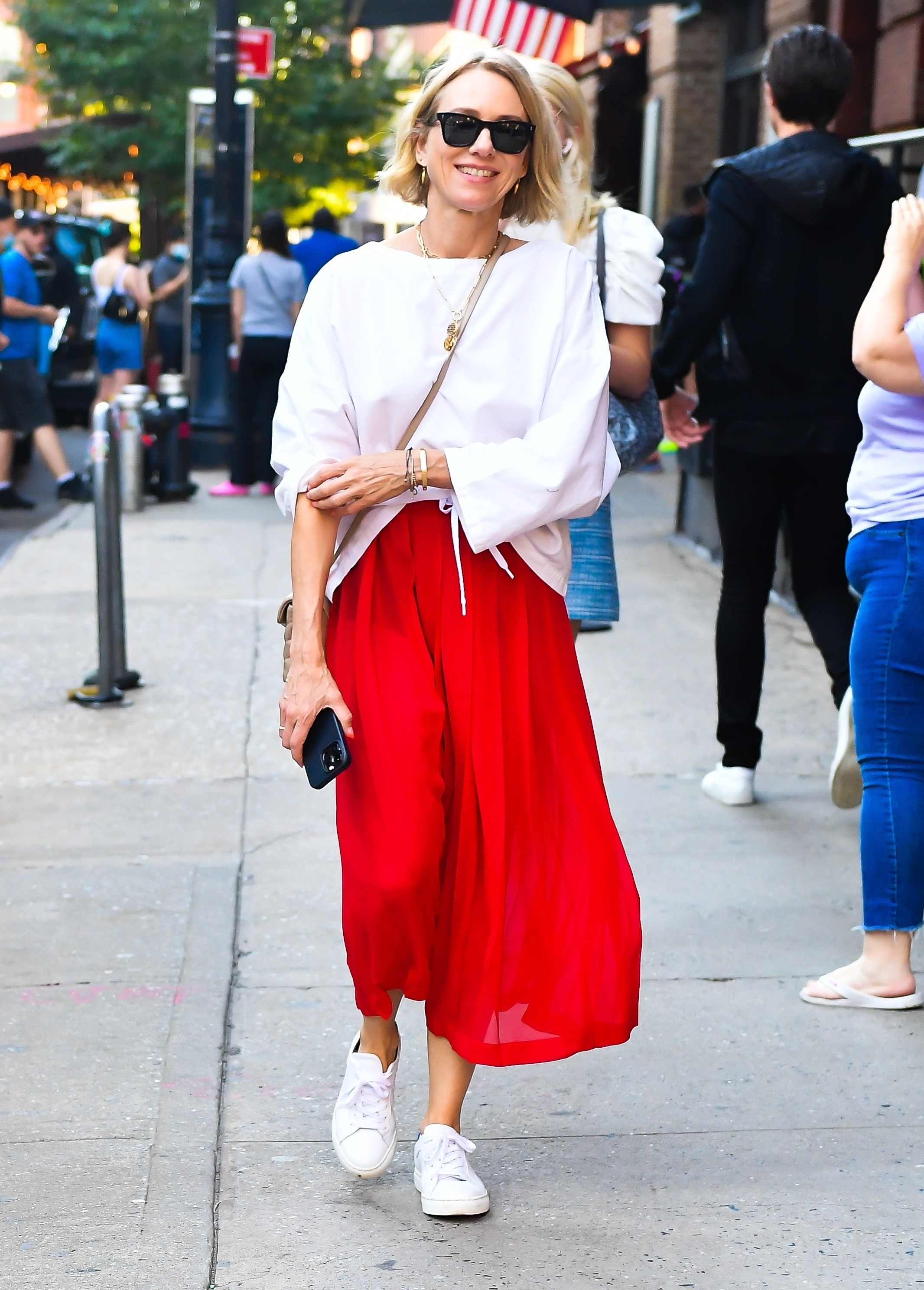 Naomi Watts was photographed when she arrived at an exclusive restaurant in New York, where she met a group of friends to eat.  She wore a red skirt with a white camisole that she paired with her leather sneakers.  In addition, she wore a shoulder bag and sunglasses.