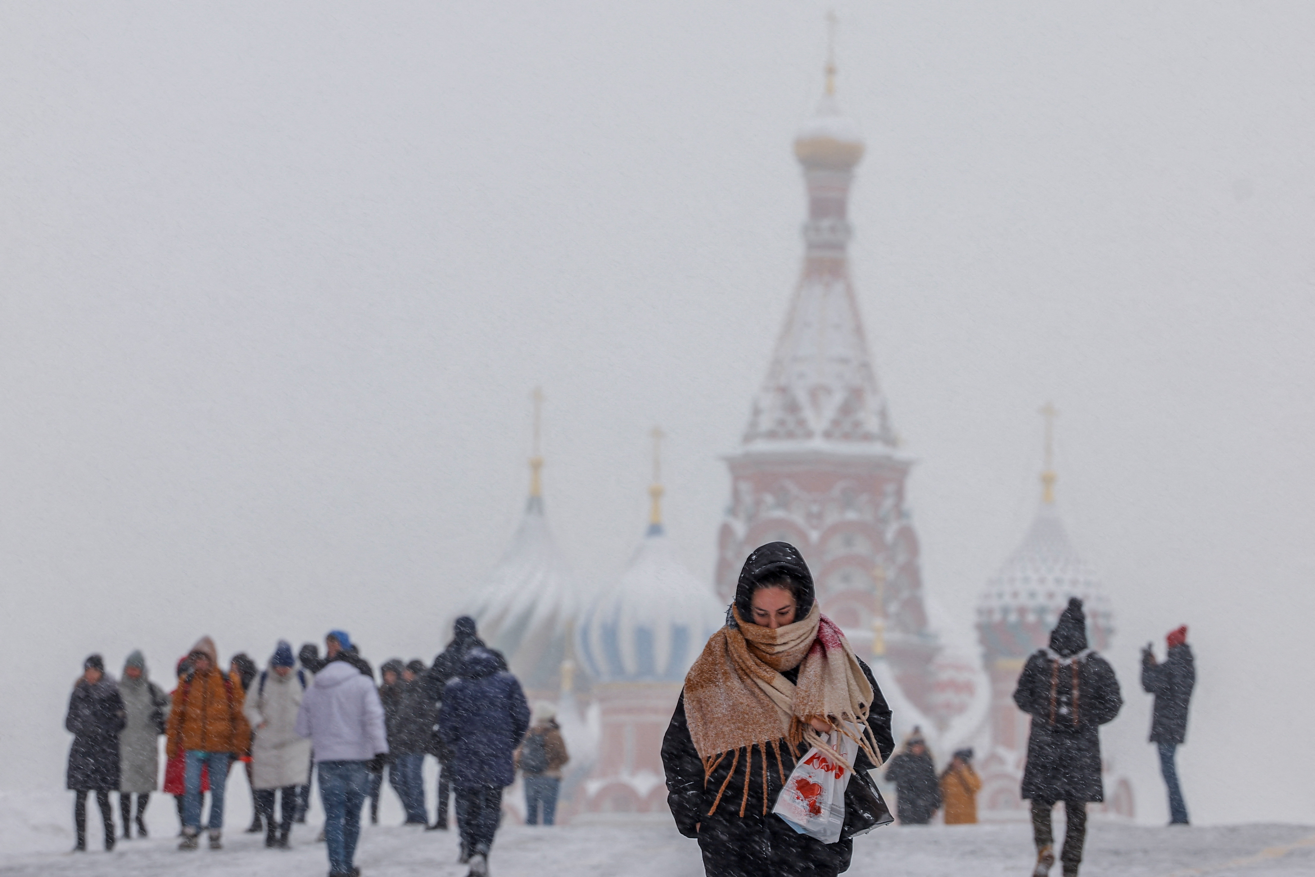 Una mujer camina por la Plaza Roja, con la Catedral de San Basilio al fondo, durante la nevada en Moscú, Rusia, el 14 de diciembre de 2022