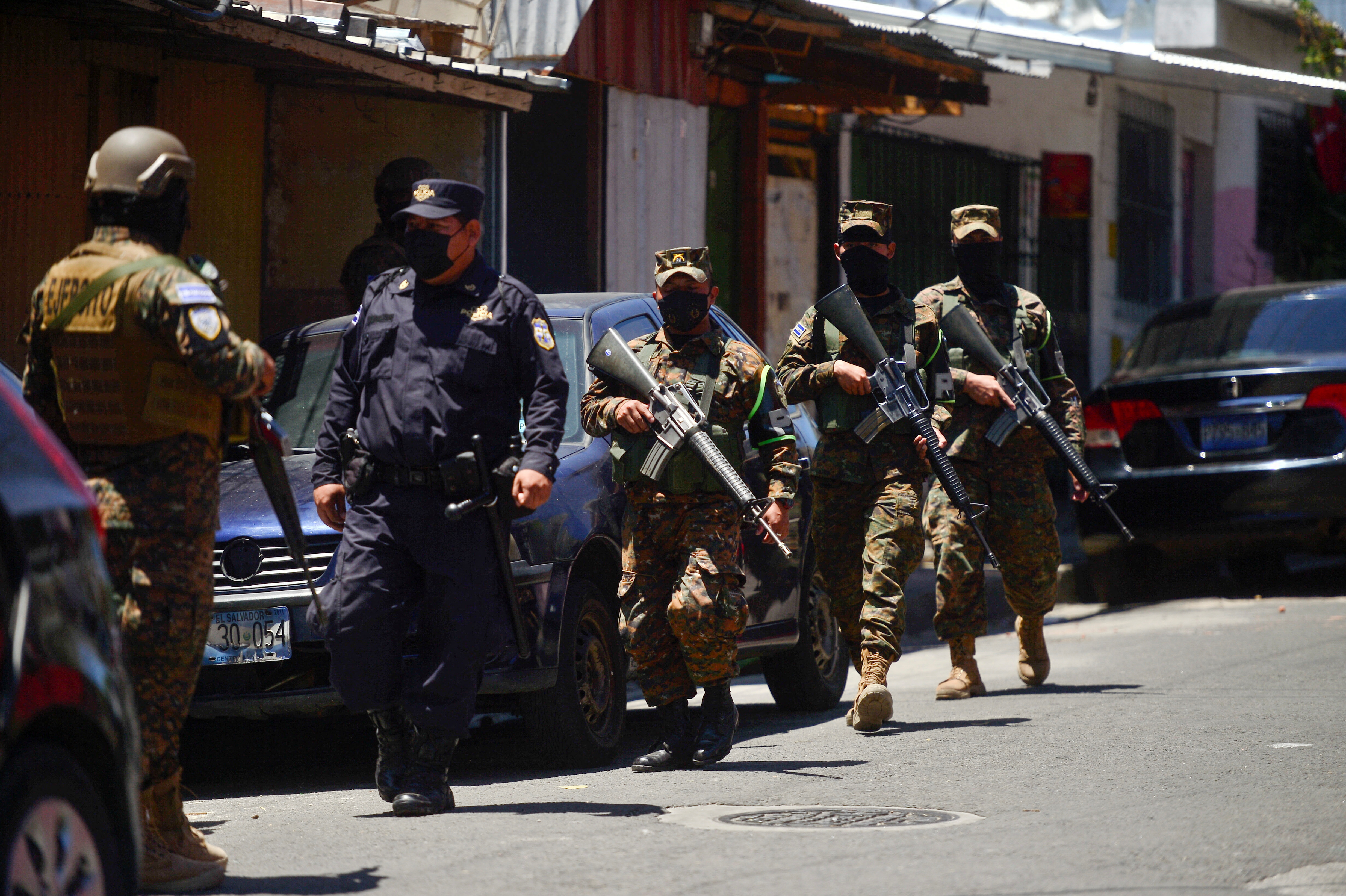 A police officer walks near soldiers along a street during a patrol after El Salvador's Congress approved on Sunday emergency powers that temporarily suspended some constitutional protections after the Central American country recorded a sharp rise in killings attributed to criminal gangs, in San Salvador, El Salvador, March 27, 2022. REUTERS/Jessica Orellana