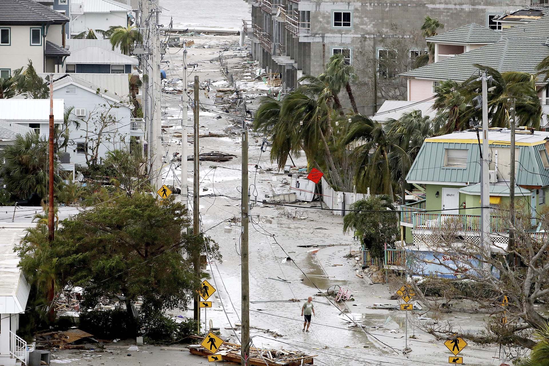 Un hombre camina por una calle entre escombros, y casas y negocios de danados en Fort Myers Beach, Florida, el jueves 29 de septiembre de 2022, tras el paso del huracán Ian. (Douglas R. Clifford/Tampa Bay Times via AP)
