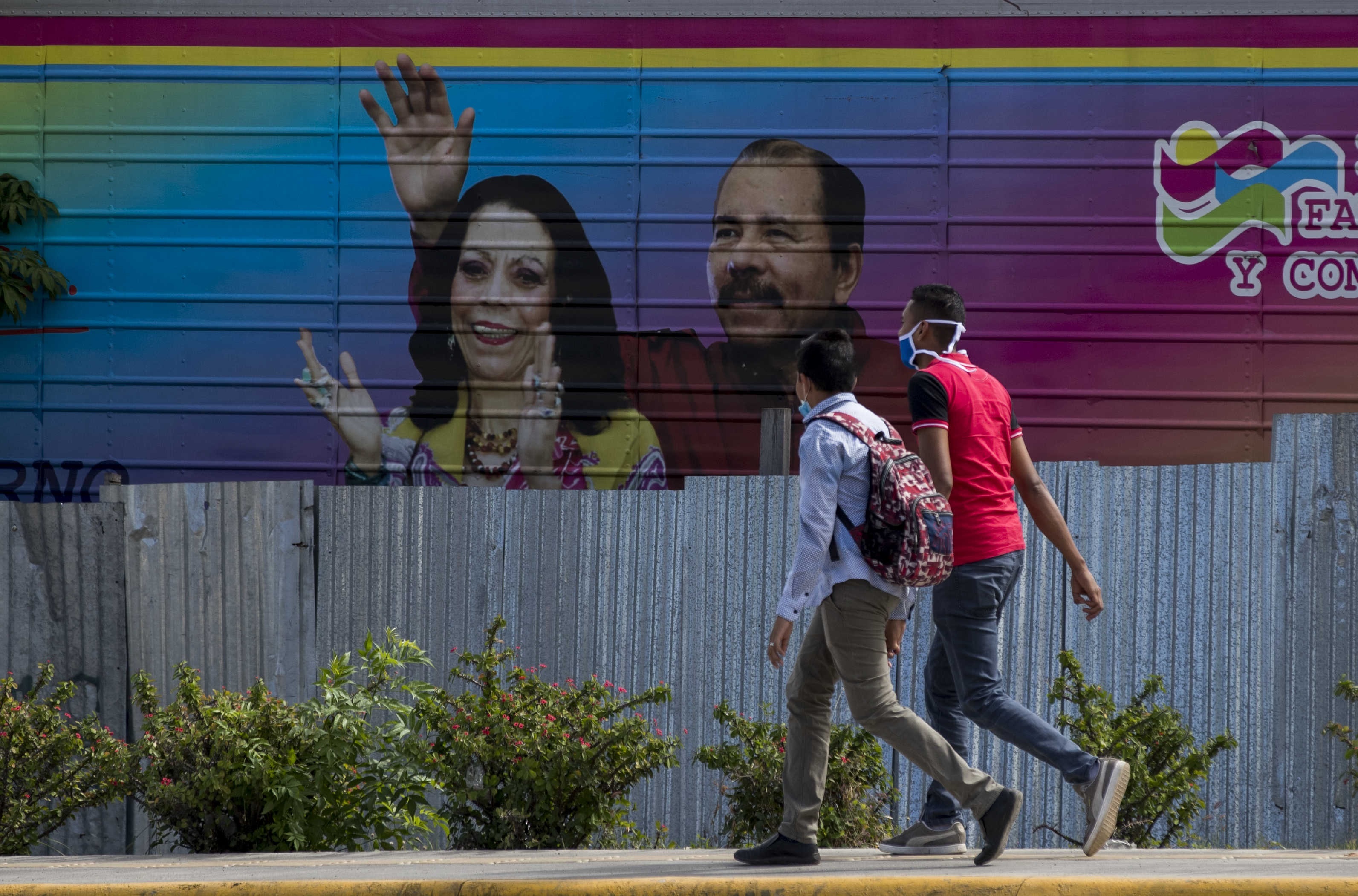 Dos jóvenes caminan frente una pancarta con la imagen de Daniel Ortega y Rosario Murillo en Managua (EFE/Jorge Torres/Archivo)
