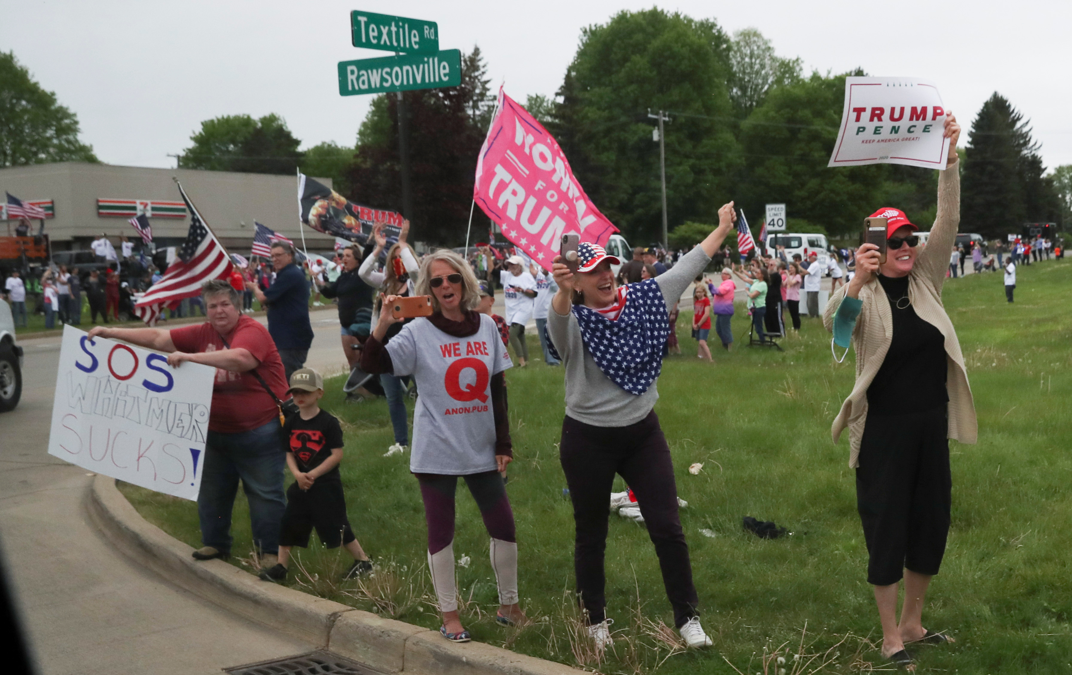 Partidarios del presidente Donald Trump y una mujer con una camiseta de QAnon animan al presidente cuando pasa en su caravana mientras se dirige a visitar la planta de componentes de Ford Rawsonville, en Ypsilanti, Michigan, EE.UU., el 21 de mayo de 2020 (REUTERS/Leah Millis)