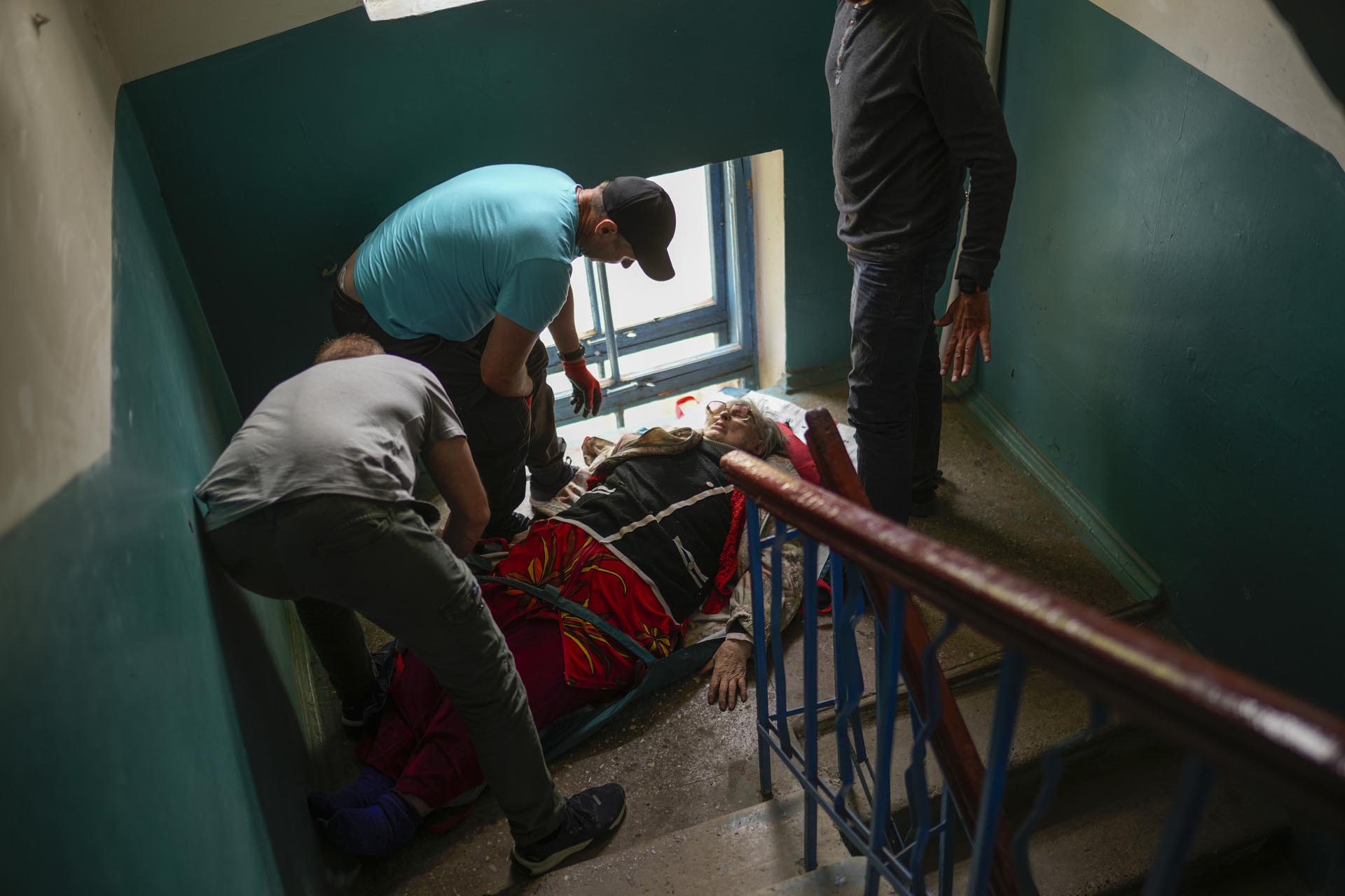 Una mujer es trasladada escaleras abajo desde su casa durante una evacuación realizada por voluntarios del grupo benéfico Vostok SOS en Kramatorsk, en el este de Ucrania, el jueves 26 de mayo de 2022. 