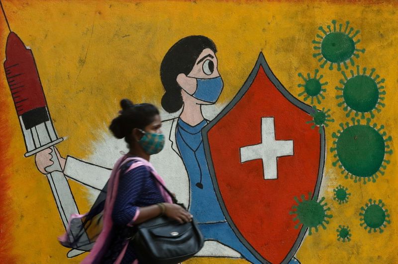 Una mujer camina frnete a un grafiti en una calle, en medio de la pandemia de COVID-19, en Mumbai, India (Reuters)
