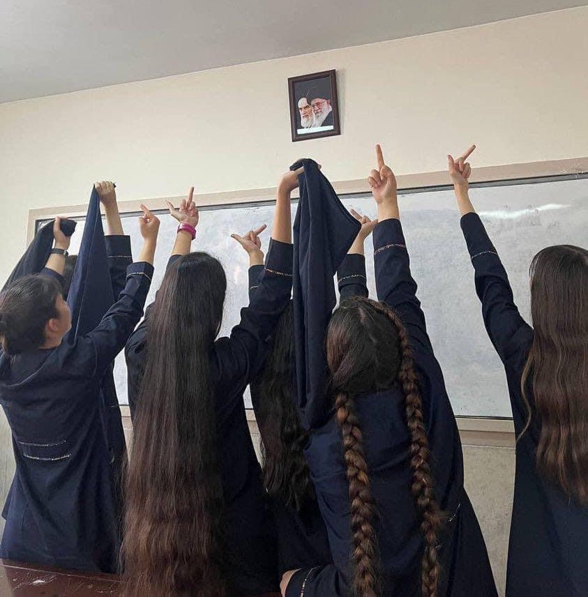 Un grupo de chicas de una escuela secundaria de Irán muestran su repudio al retrato de los ayatollahs Khomeini y Khamenei por la imposición de vestir un pañuelo que les cubra la cabeza y el cabello. (Twitter)