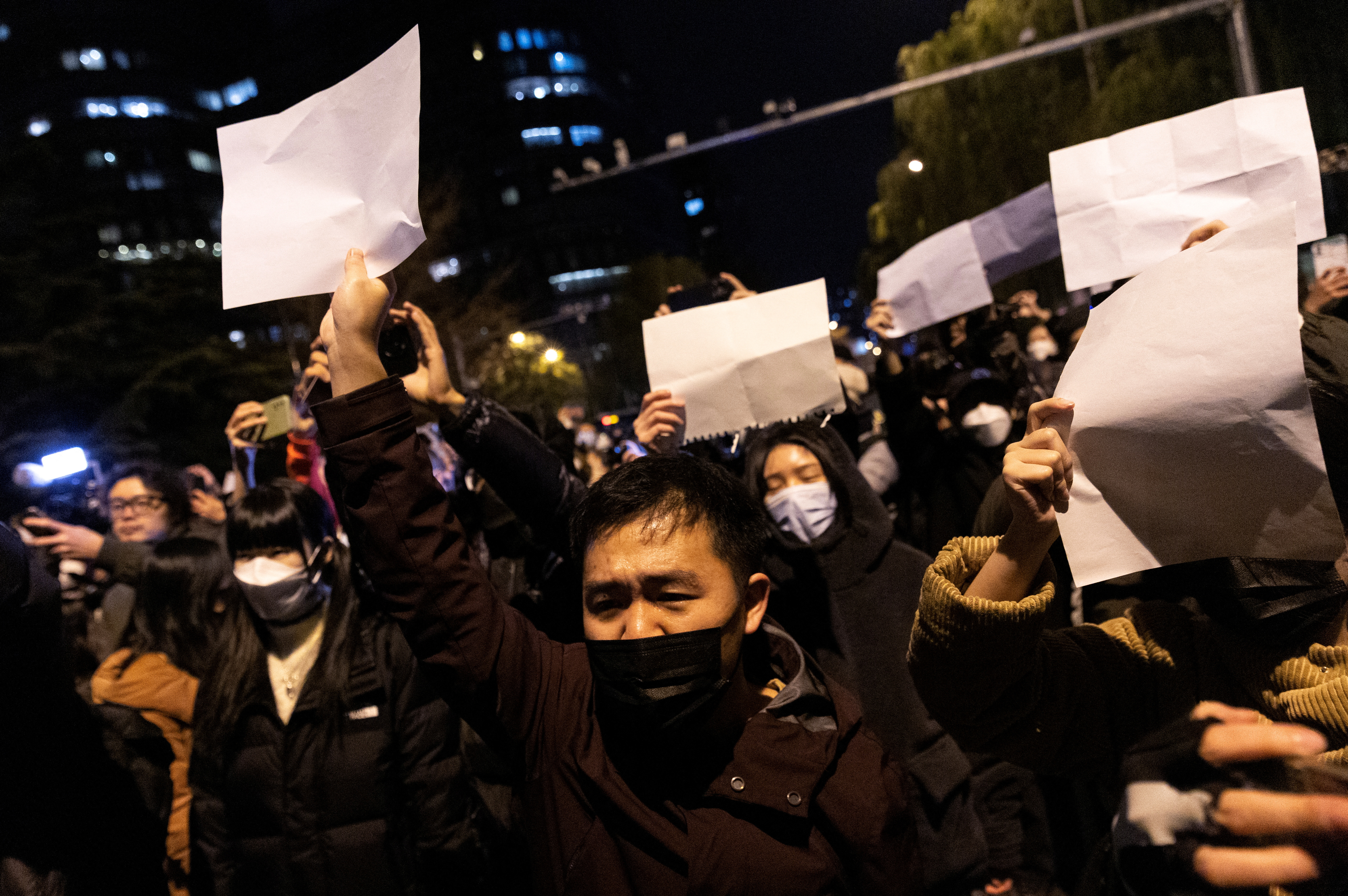 Personas sostienen hojas de papel blancas en protesta por las restricciones de COVID cero, después de una vigilia por las víctimas de un incendio en Urumqi "REUTERS POY" PARA TODOS LOS MEJORES PAQUETES DE 2022.