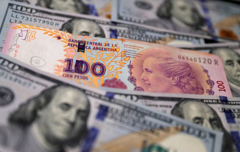 Foto de archivo: un billete de 100 pesos argentinos sobre billetes de 100 dólares