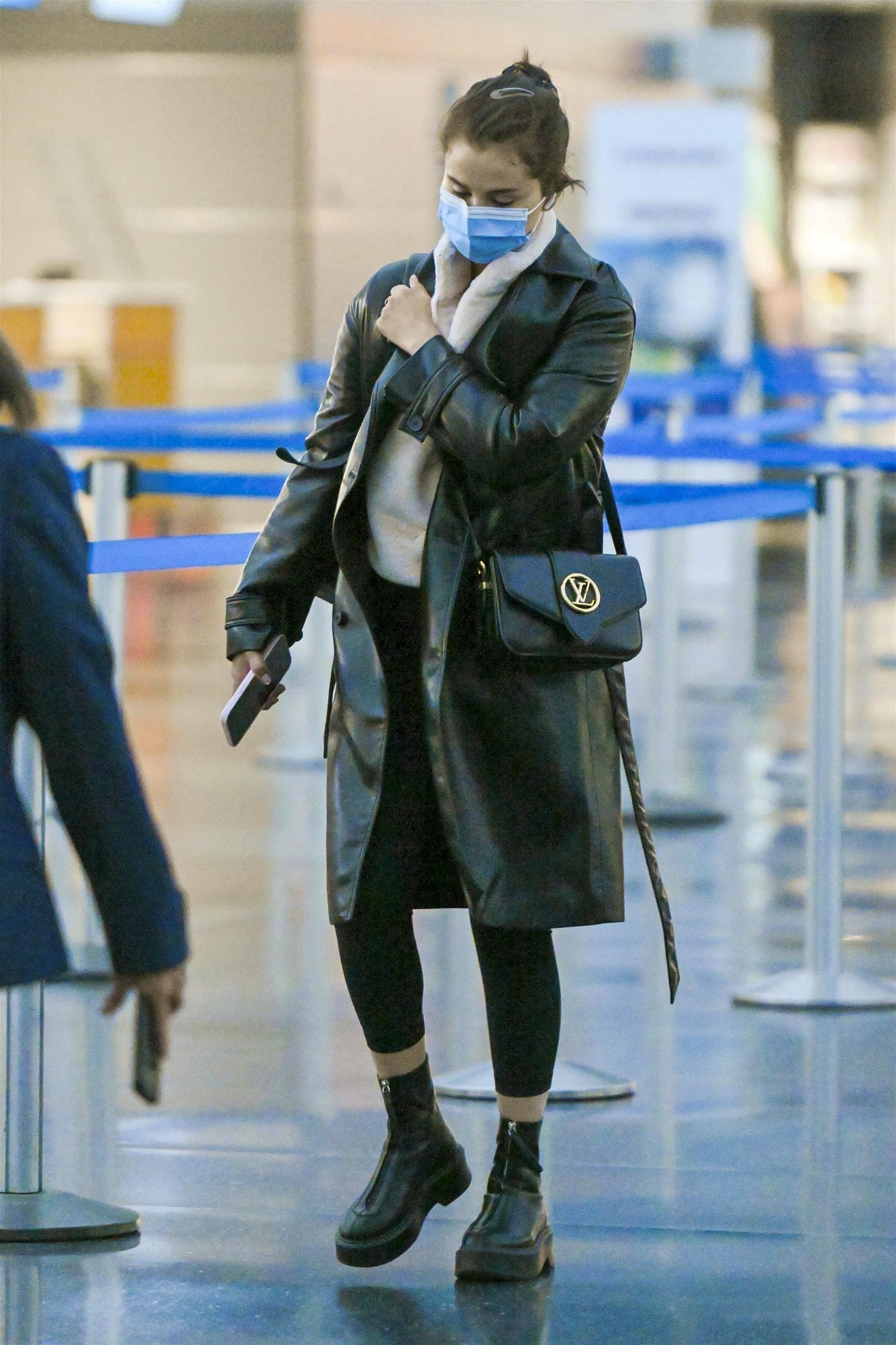 Selena Gomez tried to keep a low profile as she walked through New York's JFK airport.  The artist fulfilled work commitments.  She wore a comfortable look to travel, black tights that she combined with her coat, boots and bag, and a light-colored diver