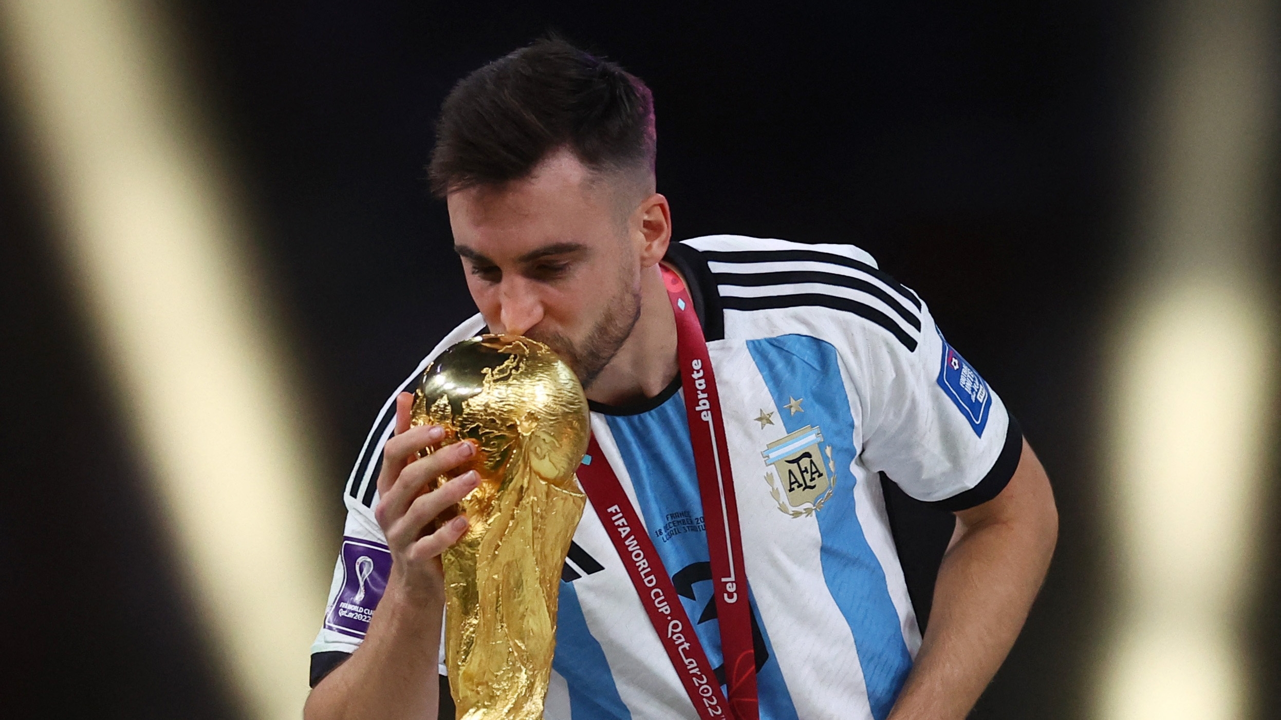 Soccer Football - FIFA World Cup Qatar 2022 - Final - Argentina v France - Lusail Stadium, Lusail, Qatar - December 18, 2022 Argentina's Nicolas Tagliafico kisses the World Cup trophy after receiving his medal as he celebrates winning the World Cup REUTERS/Kai Pfaffenbach